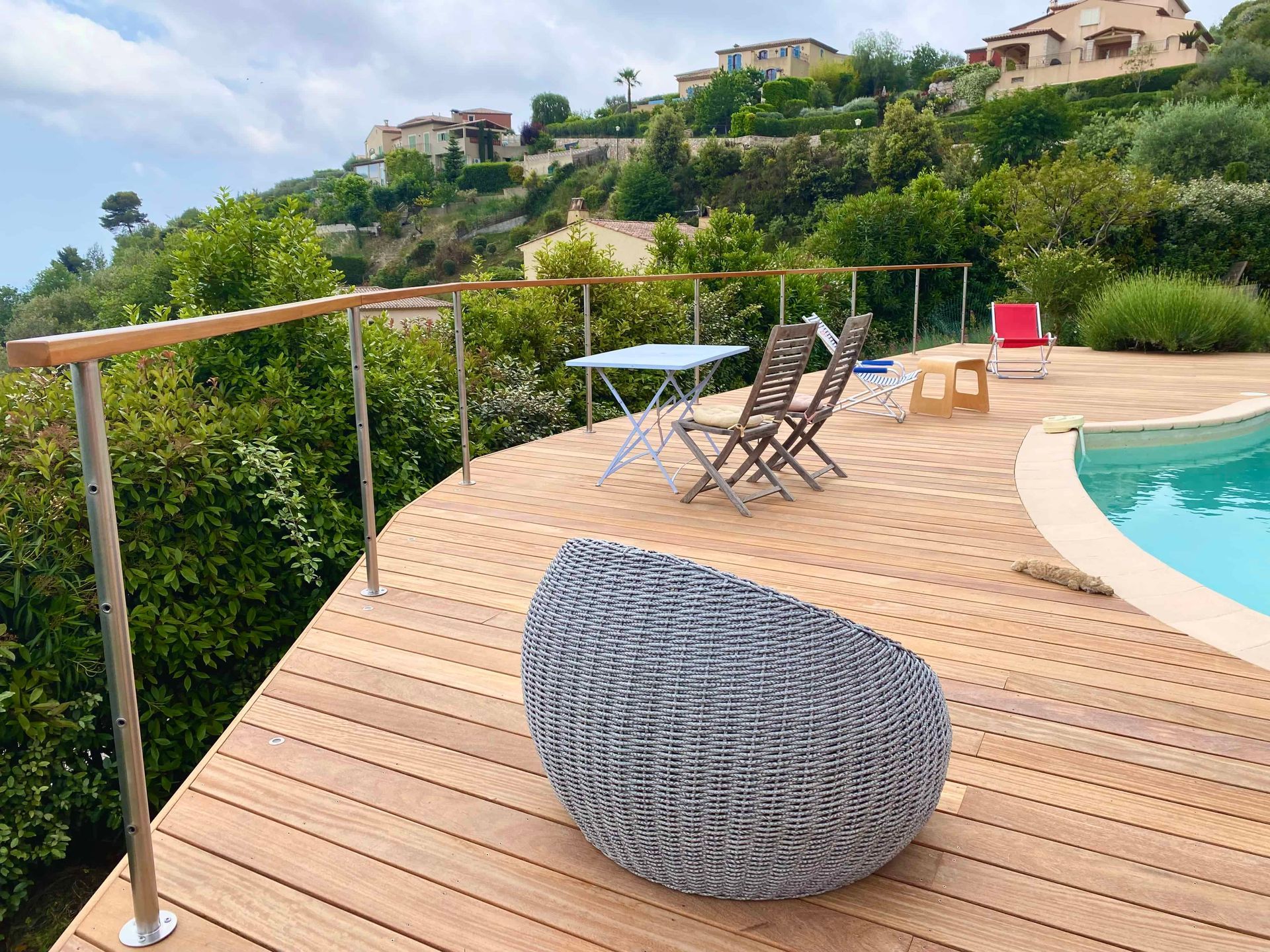 Une terrasse en bois donnant sur une piscine avec chaises et tables