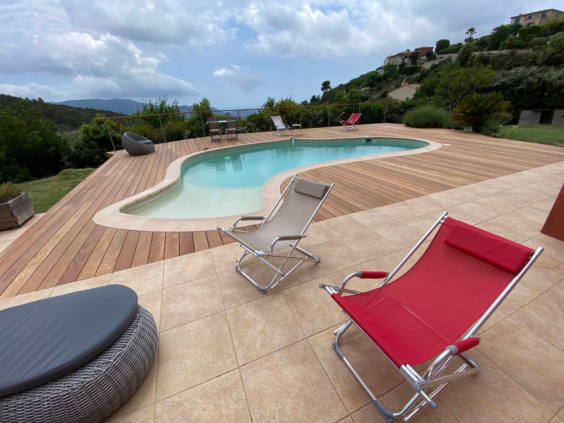 Une piscine avec une terrasse en bois et des chaises autour