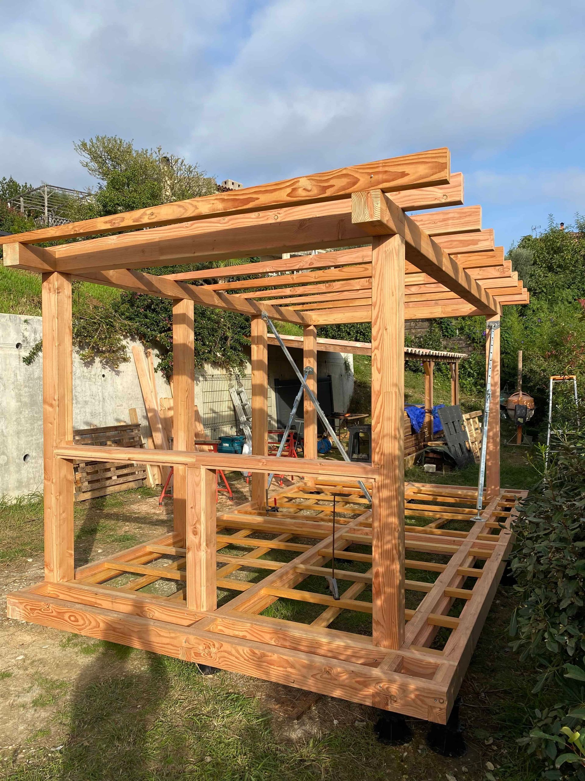 Une structure en bois est en cours de construction dans une cour arrière.