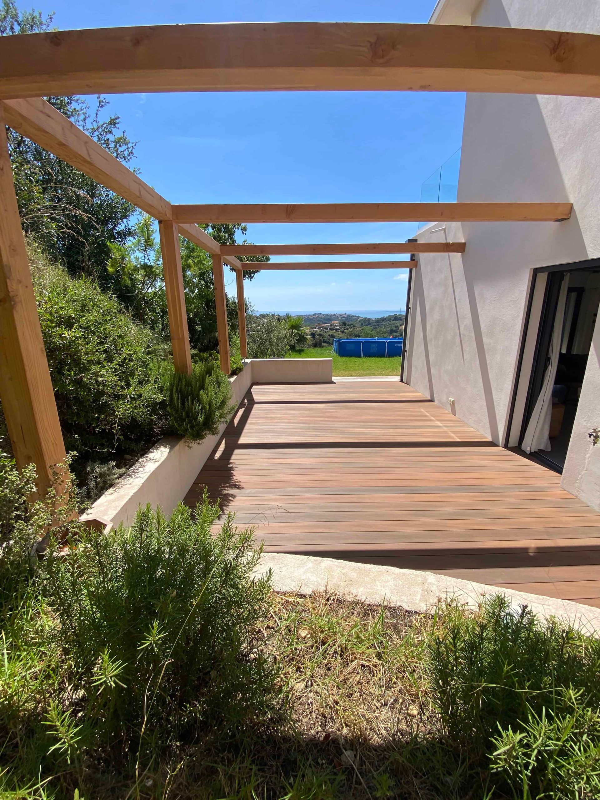 Il y a une terrasse en bois avec une pergola au-dessus.