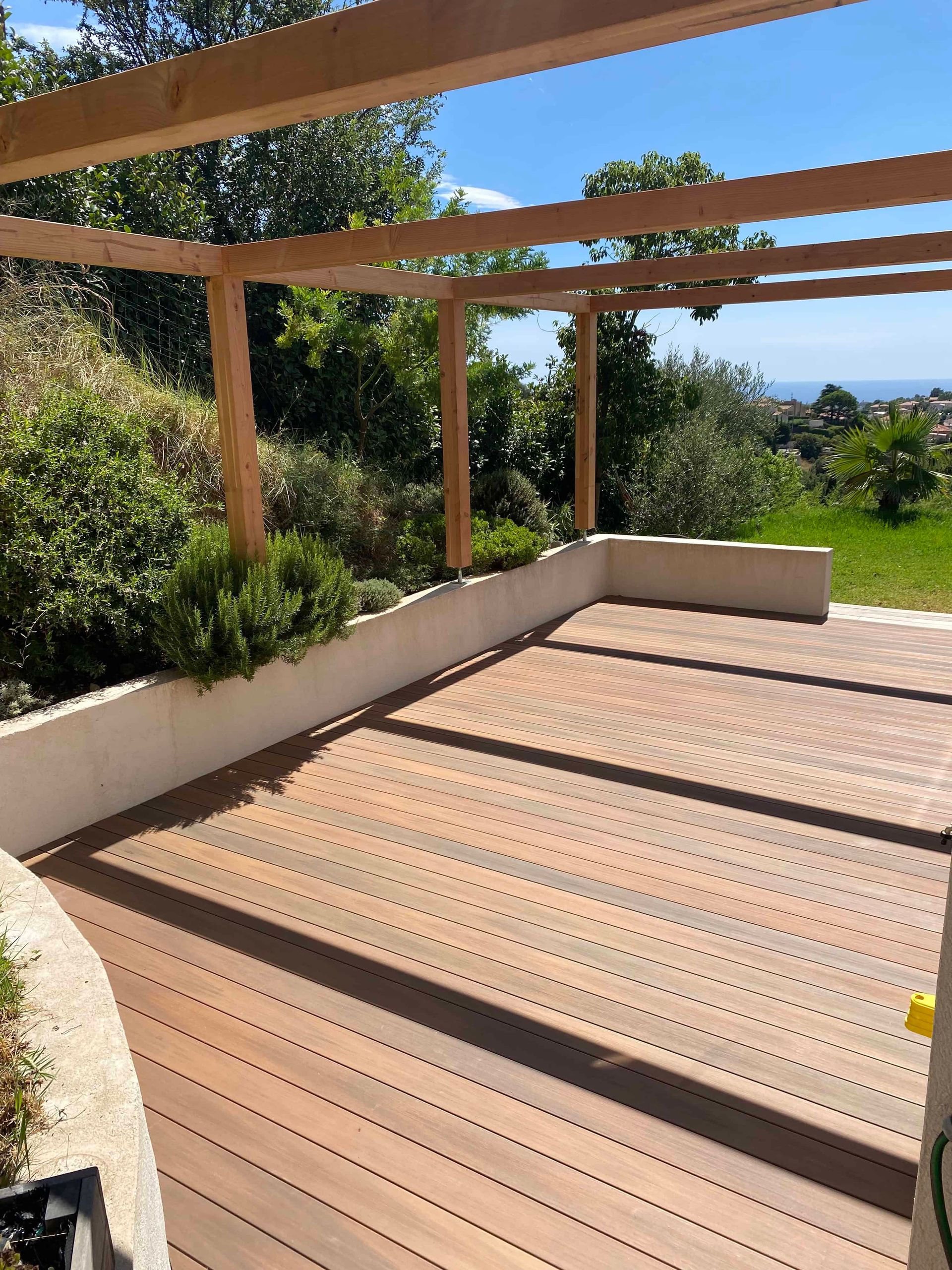 Une terrasse en bois avec une pergola et une vue sur l'océan