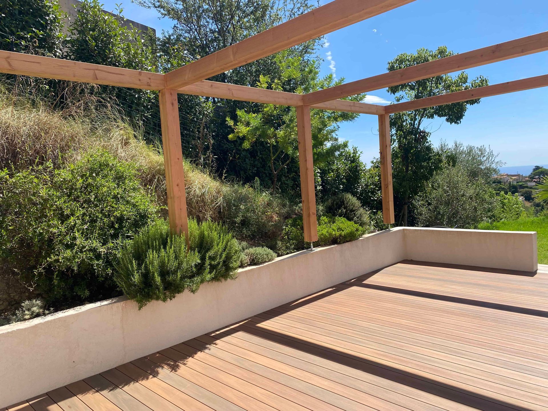Une terrasse en bois avec une pergola et des arbres en arrière-plan