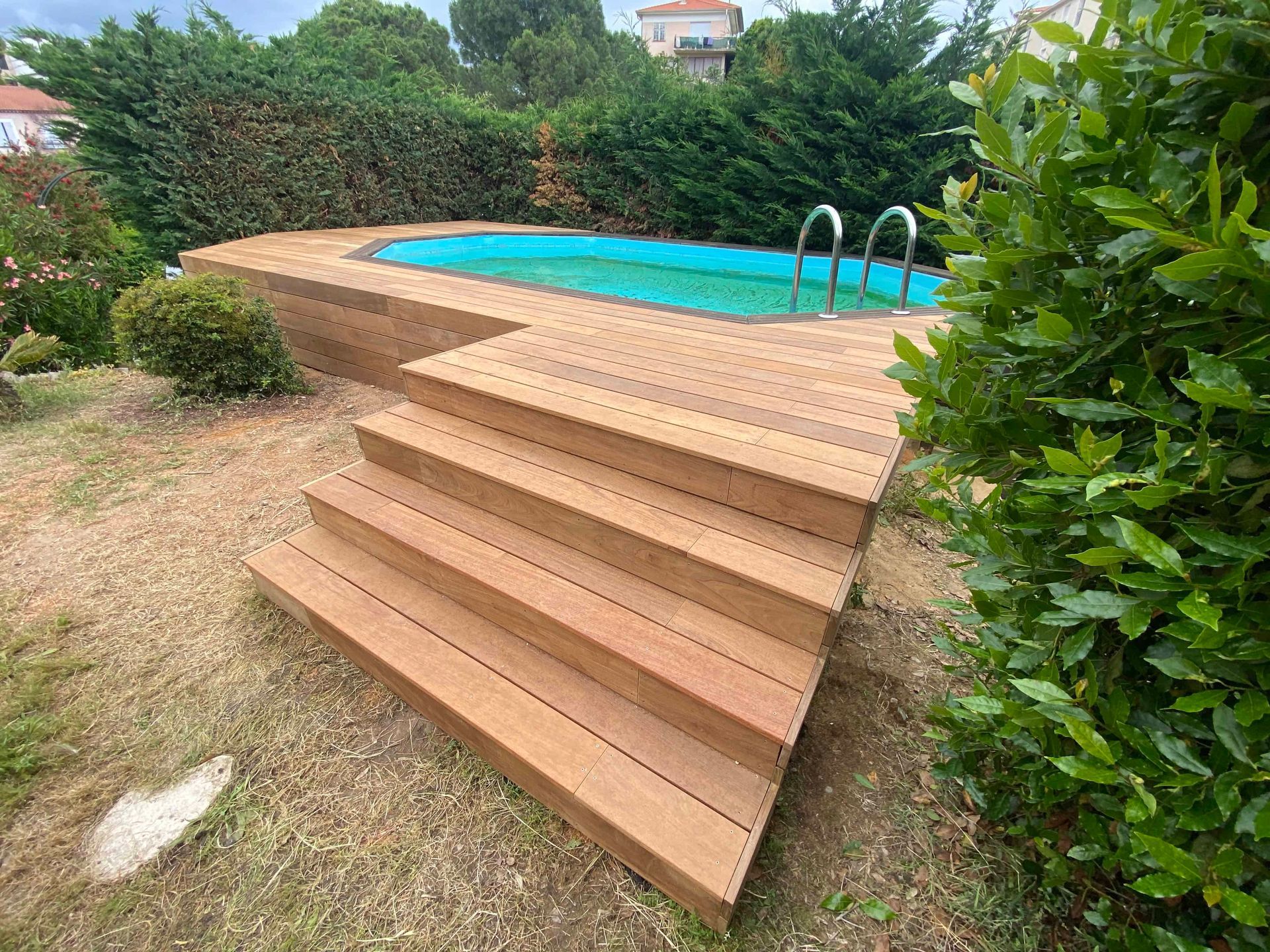 Une terrasse en bois avec des escaliers menant à une piscine.