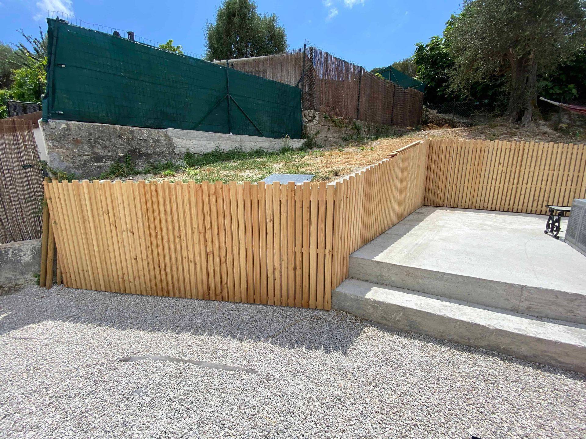 Une clôture en bois entoure une zone de gravier avec des escaliers qui y mènent.