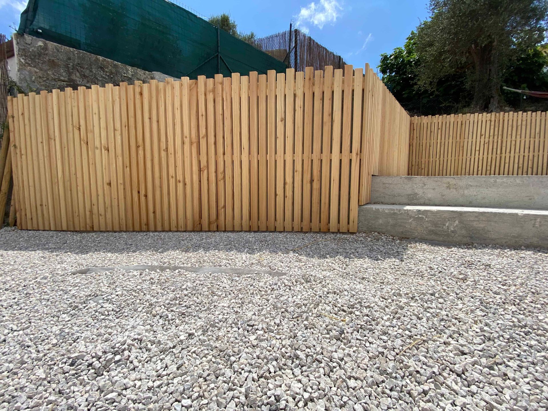 Une clôture en bois est entourée de gravier et d'escaliers