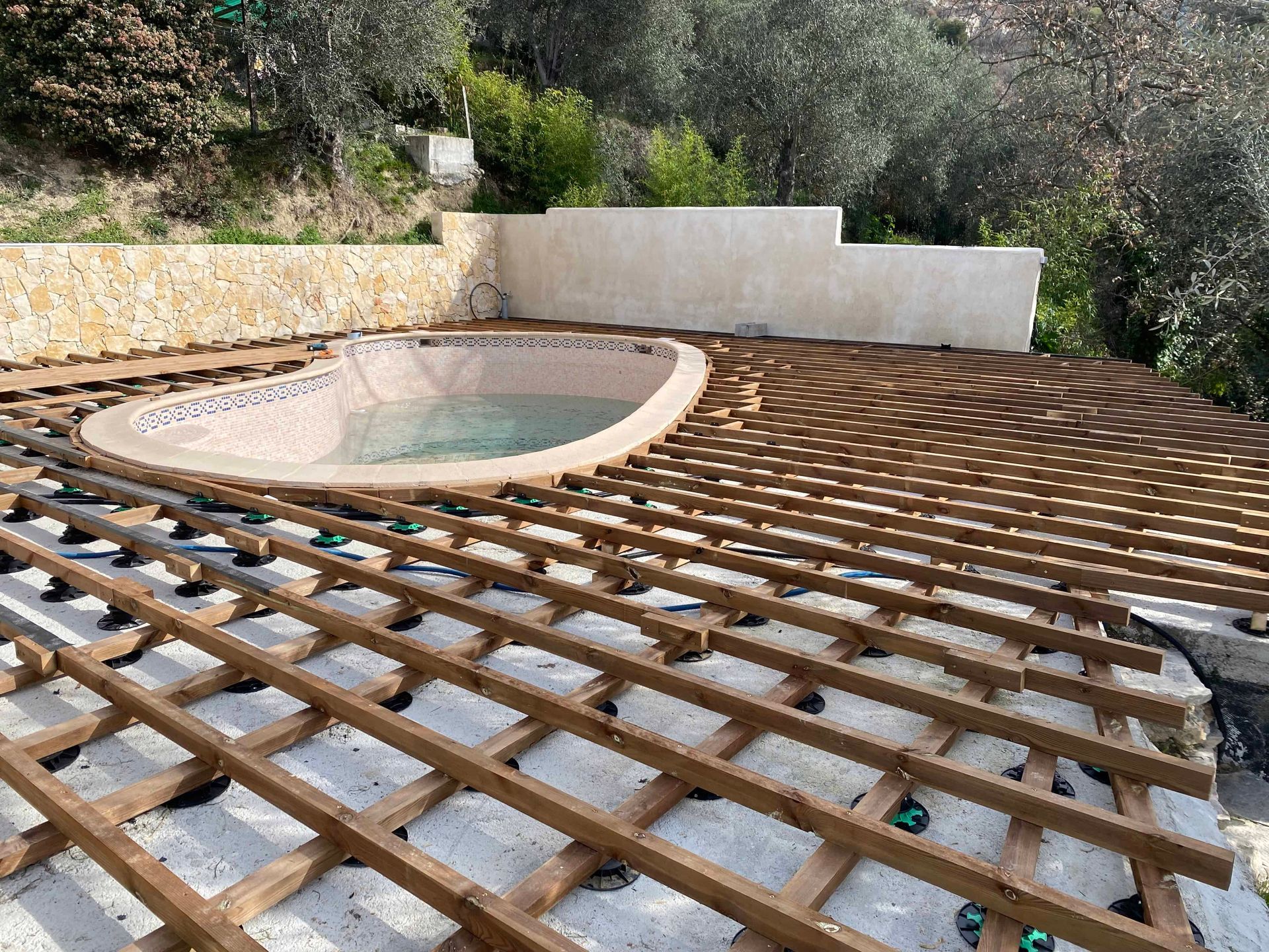 Une piscine est en cours de construction sur une terrasse en bois.