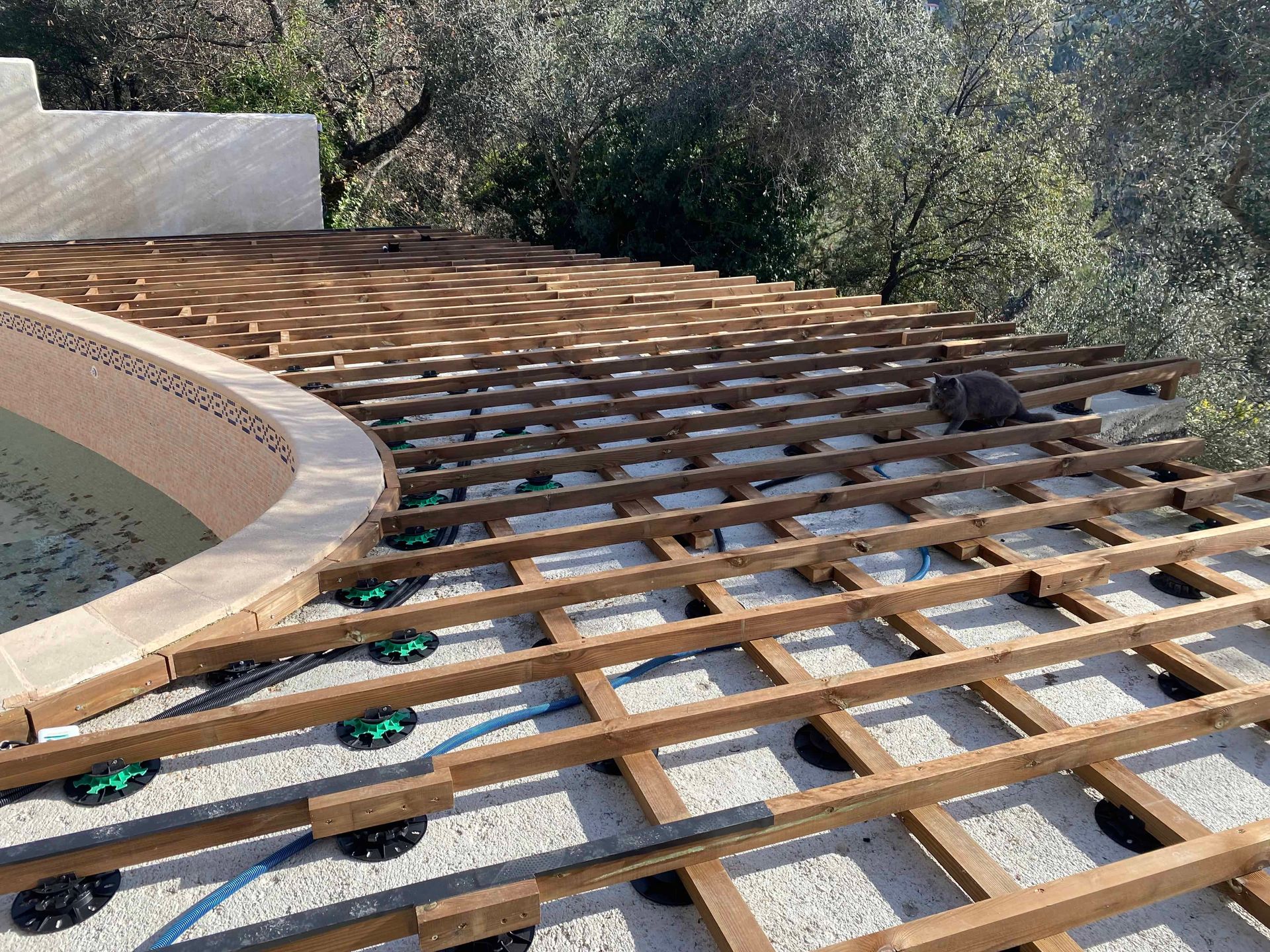 Une terrasse en bois est en cours de construction autour d'une piscine.
