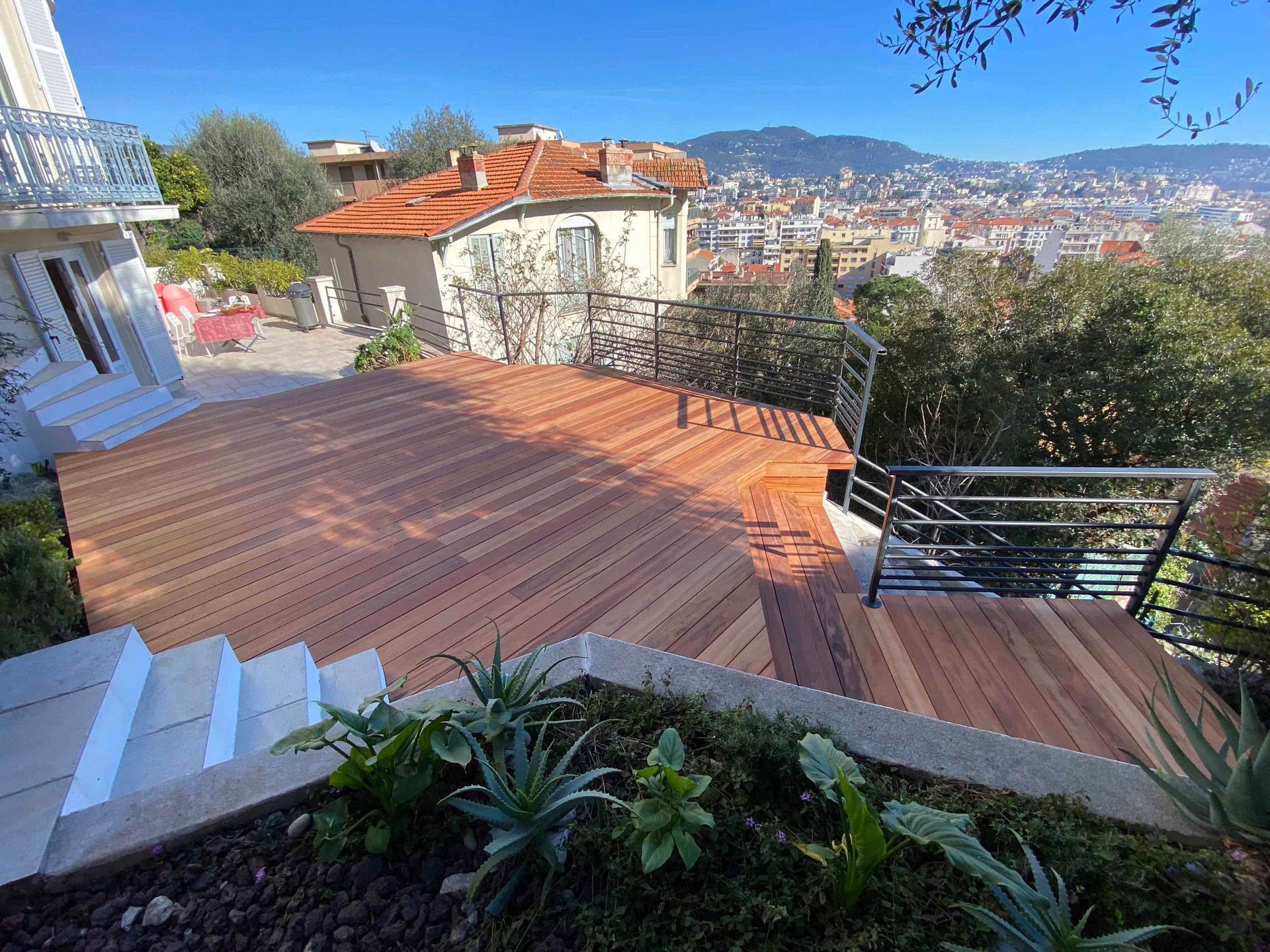 Une terrasse en bois avec des escaliers qui y mènent et une vue sur une ville.