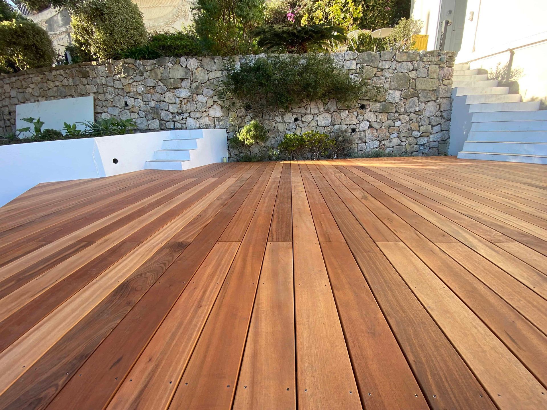 Une terrasse en bois avec un mur de pierre en arrière-plan