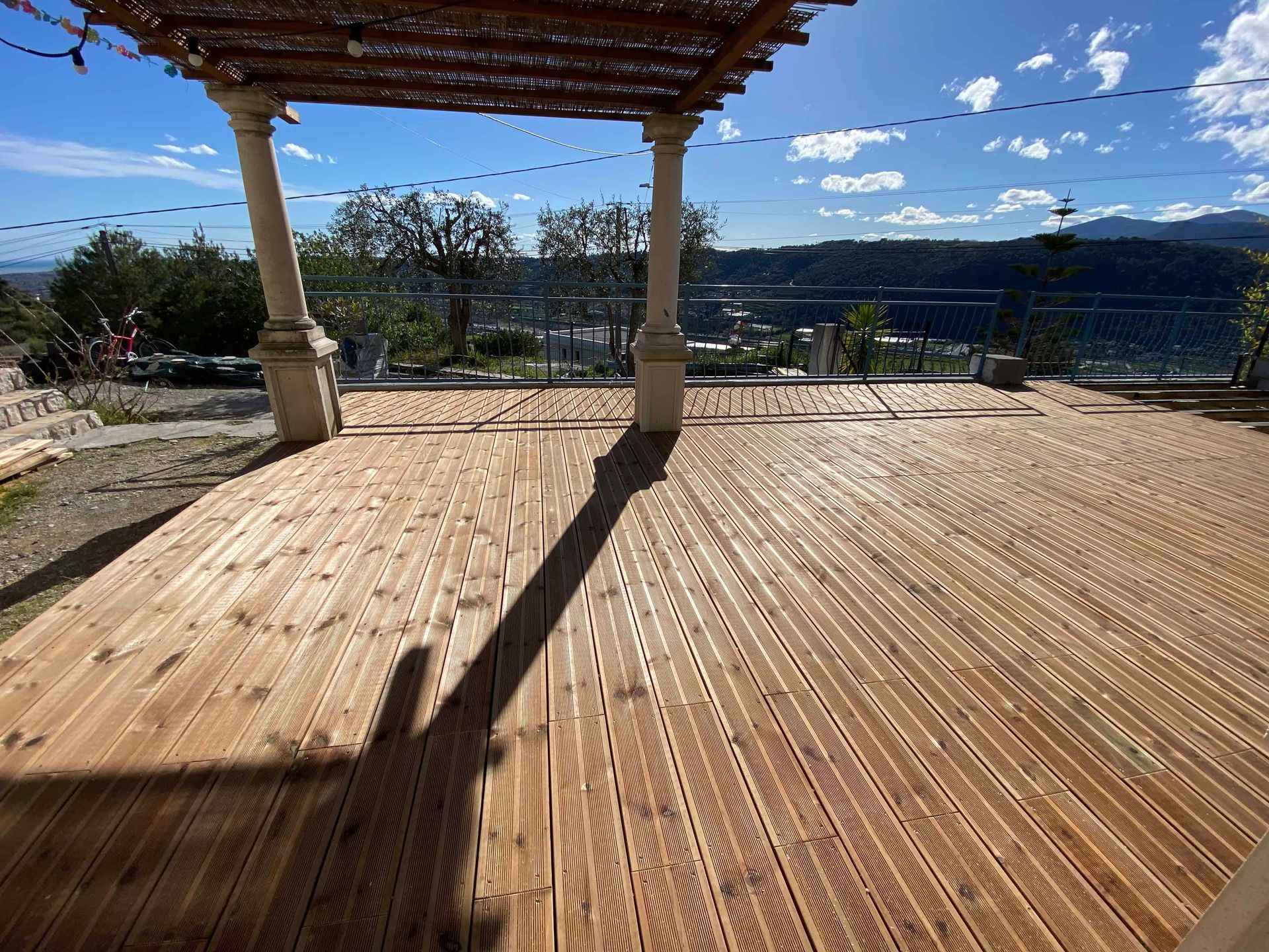 Une terrasse en bois avec une pergola en arrière-plan