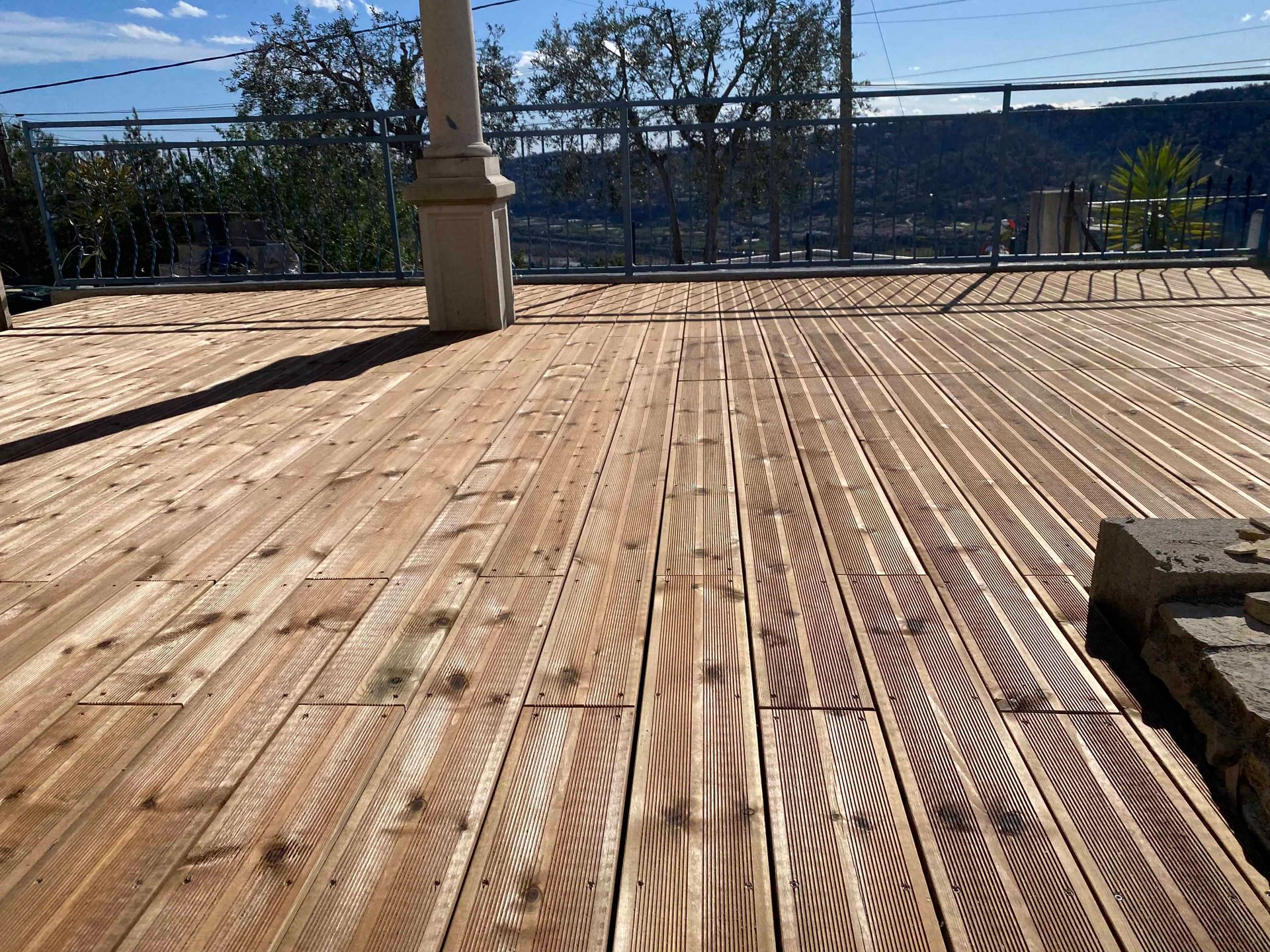 Une terrasse en bois avec une balustrade et des arbres en arrière-plan.