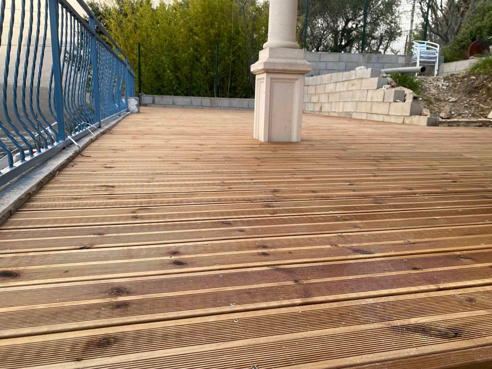 Une terrasse en bois avec une balustrade bleue et une chaise blanche.