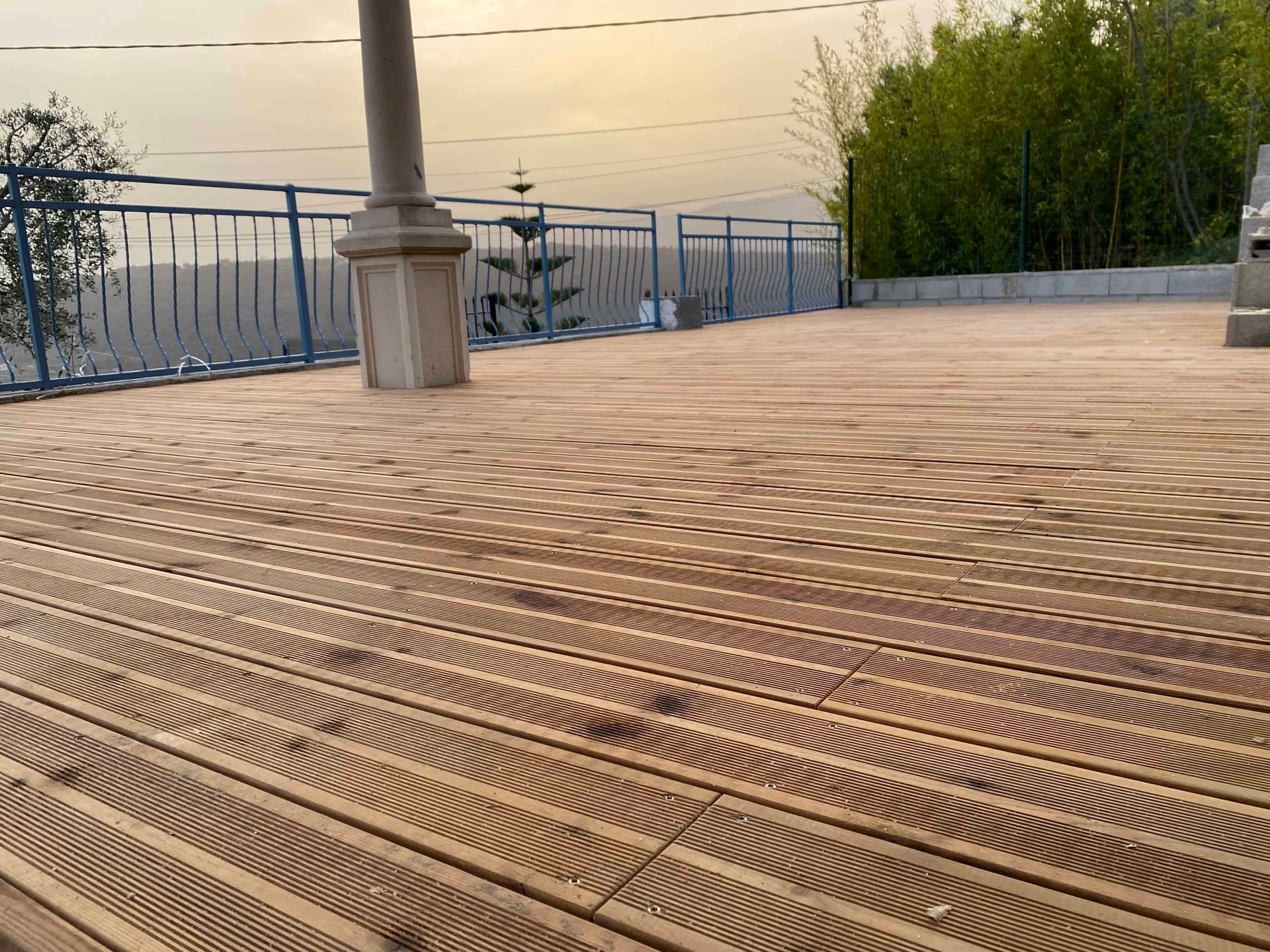 Une terrasse en bois avec une balustrade et des arbres en arrière-plan.