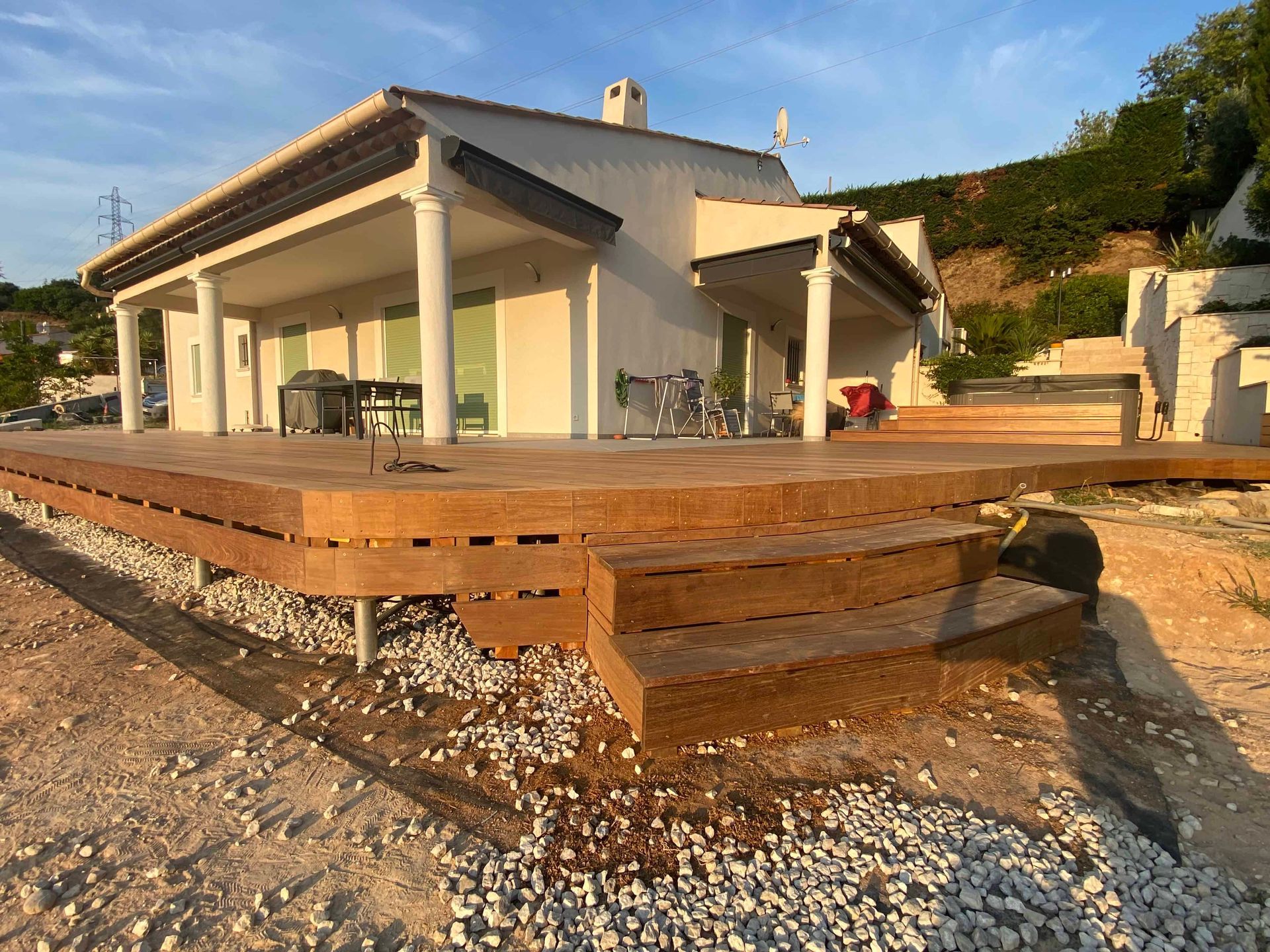 Une maison avec une terrasse en bois et des escaliers devant.