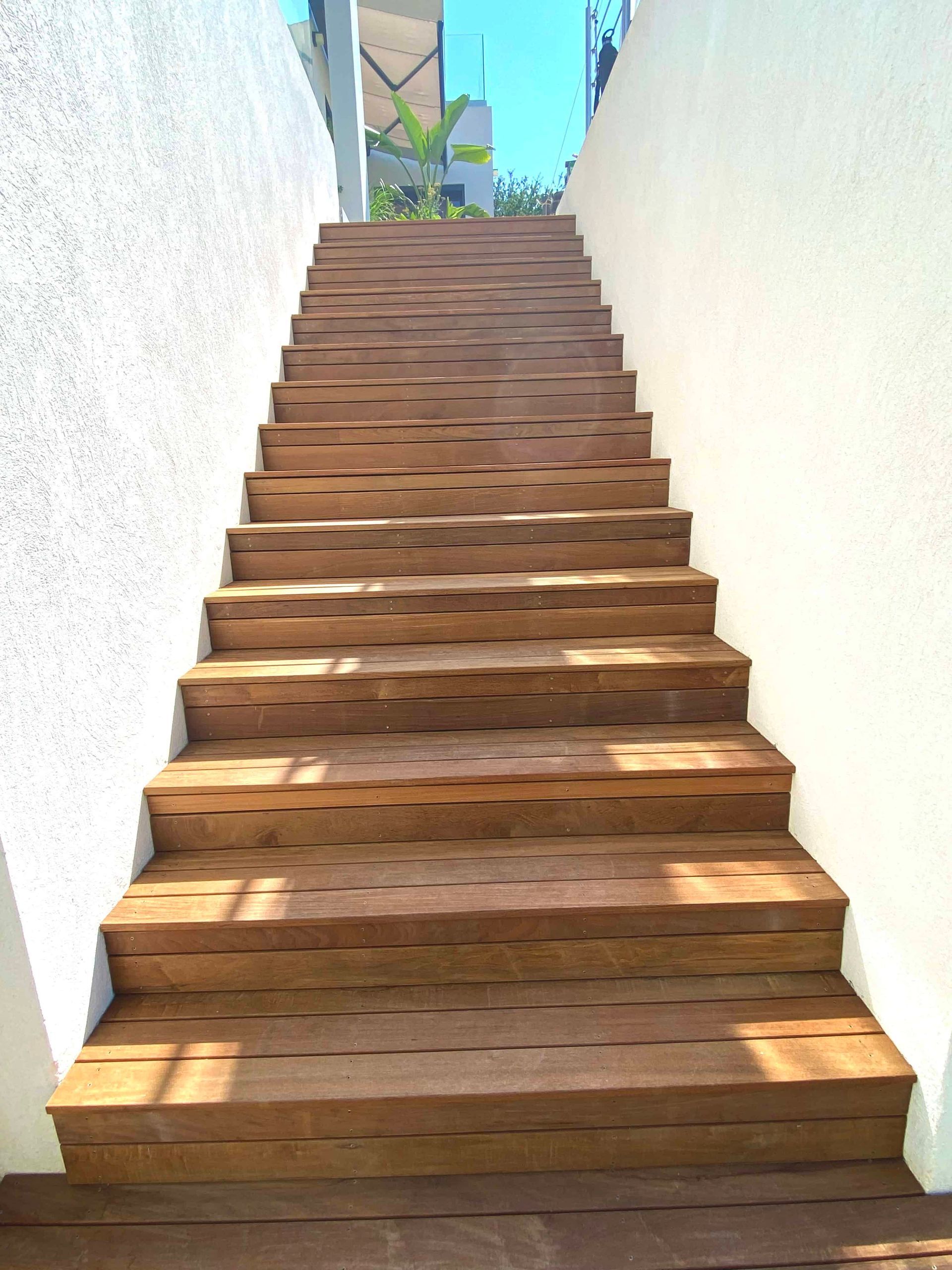 Un escalier en bois menant à un mur blanc