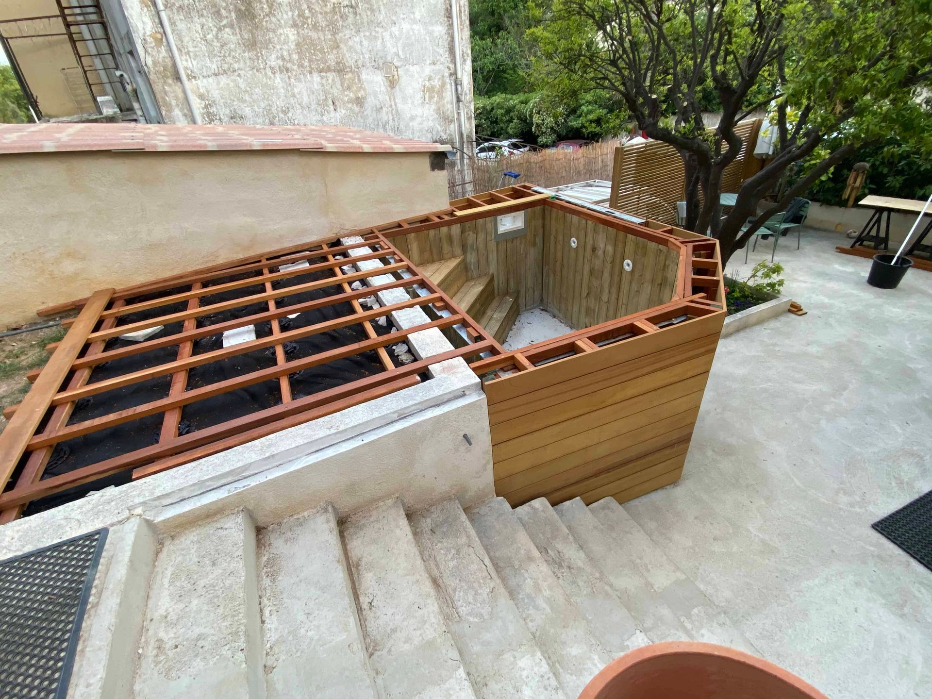 Une terrasse en bois est en cours de construction à côté d'un ensemble d'escaliers.