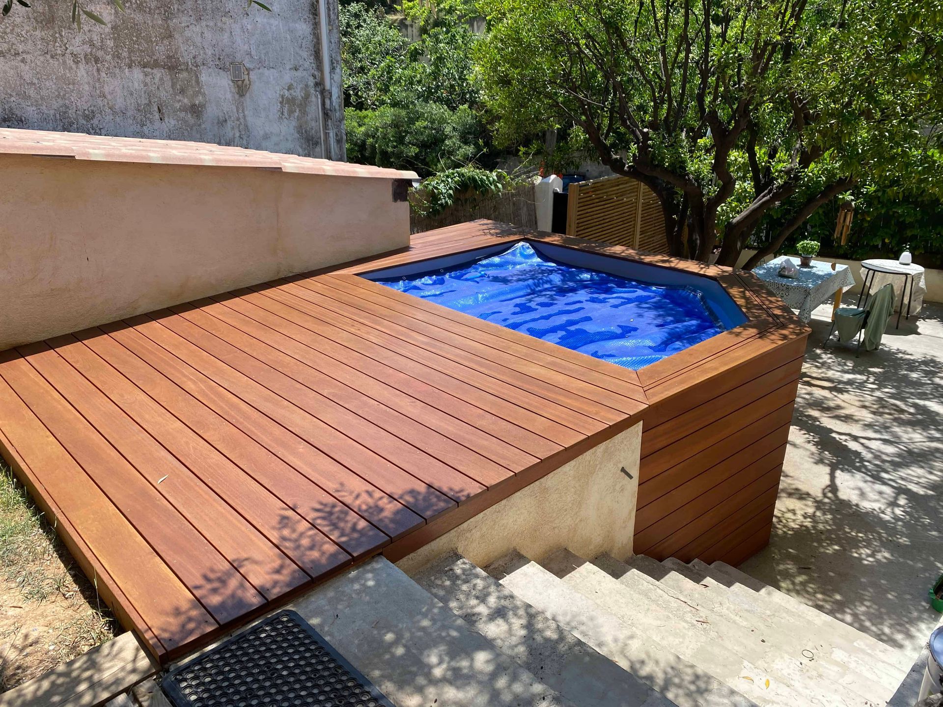 Une terrasse en bois avec une piscine en dessous