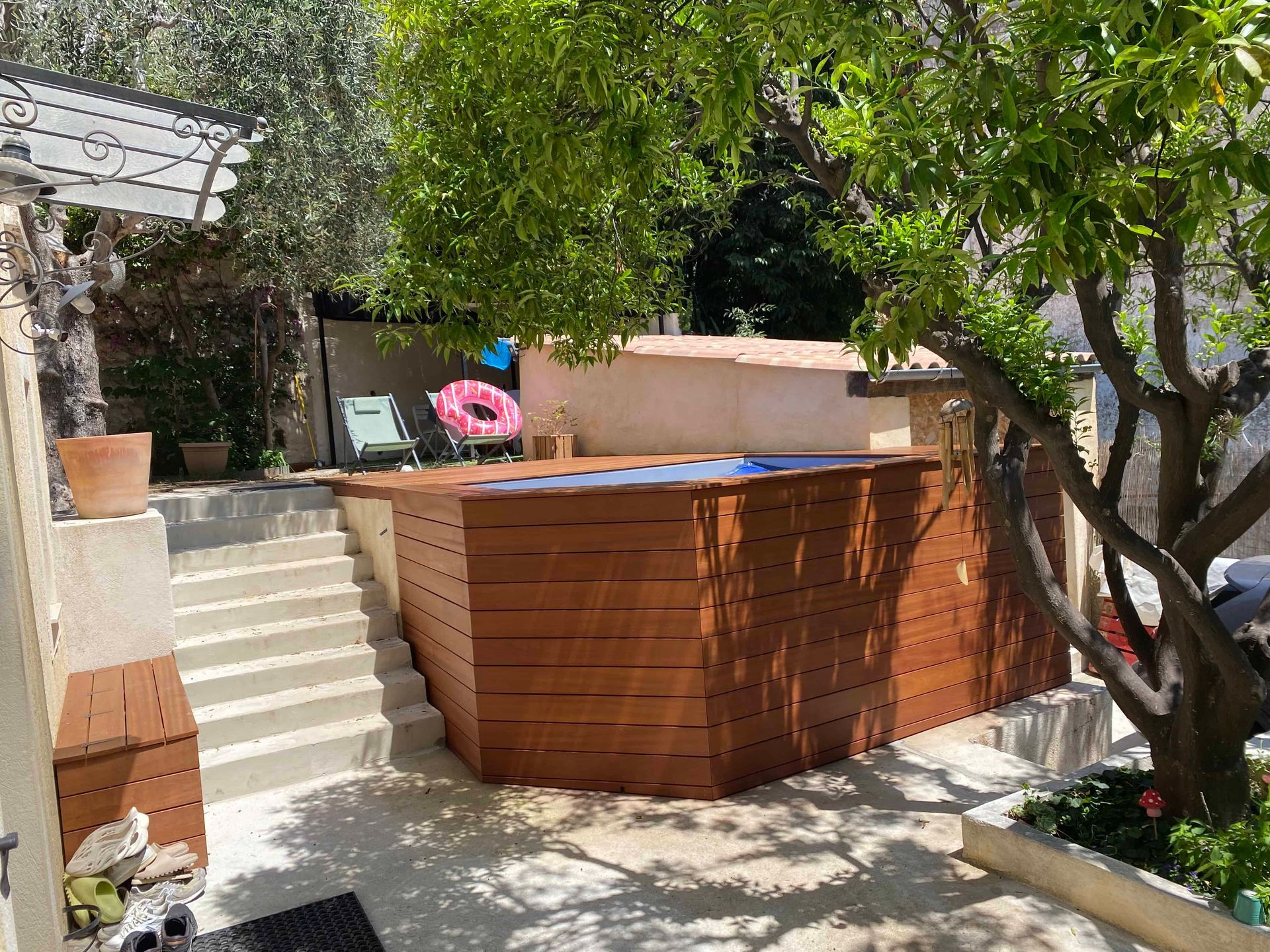 Une clôture en bois entoure une piscine dans une cour arrière.