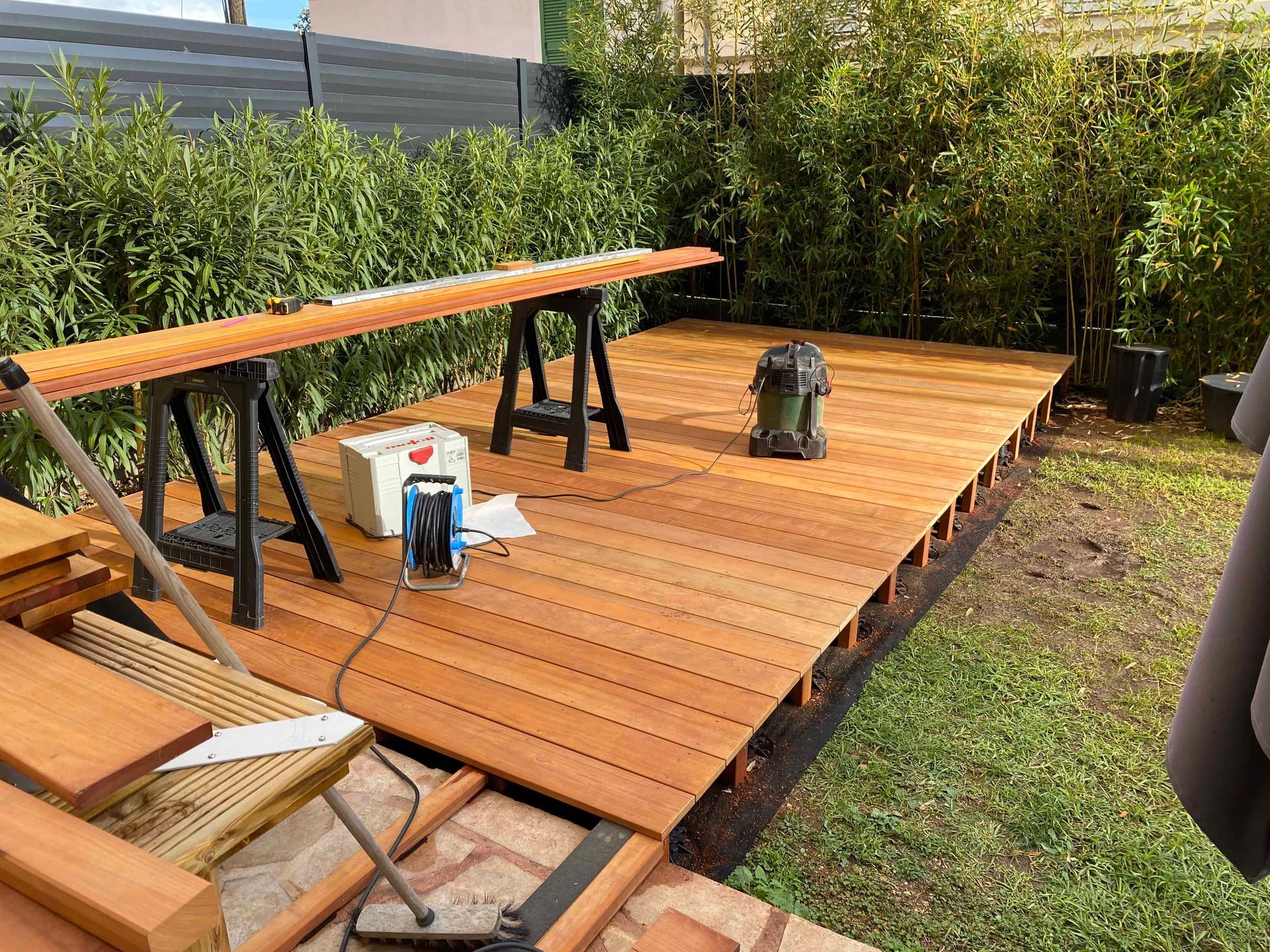 Une terrasse en bois est en cours de construction dans une cour arrière.
