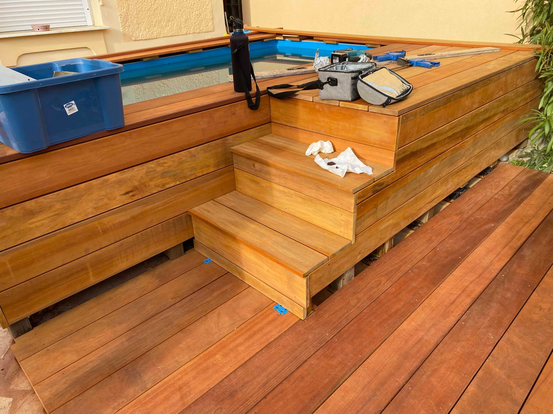 Une terrasse en bois avec des escaliers menant à une piscine.