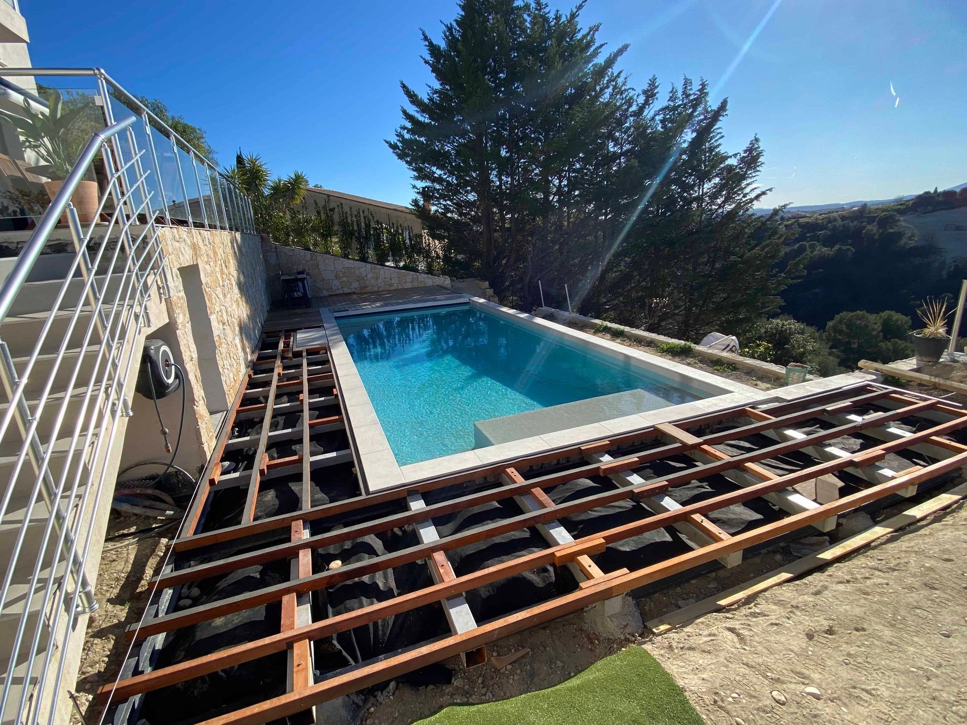 Une terrasse en bois est en cours de construction autour d'une piscine.