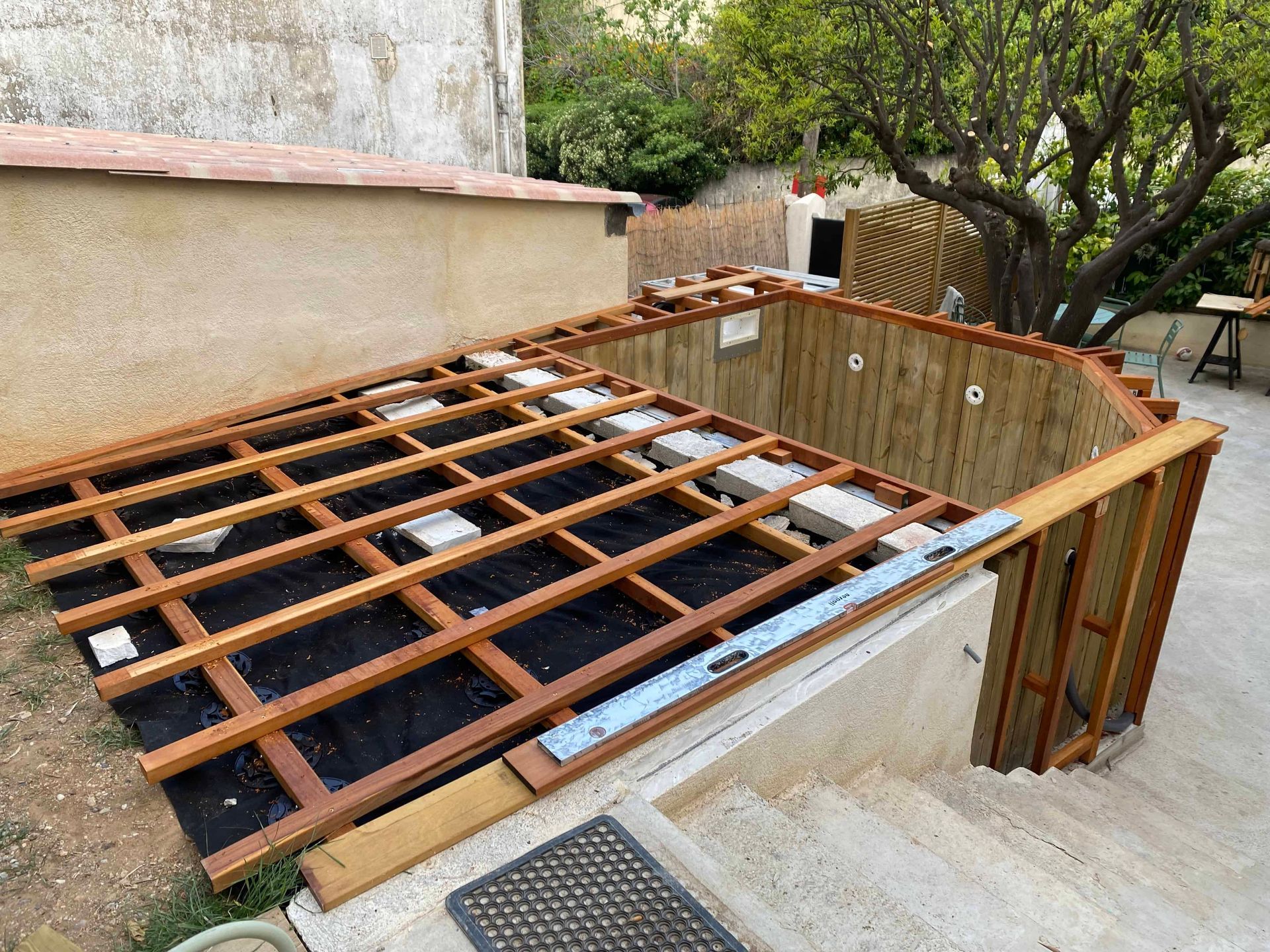 Une terrasse en bois est en cours de construction au-dessus d'une piscine.