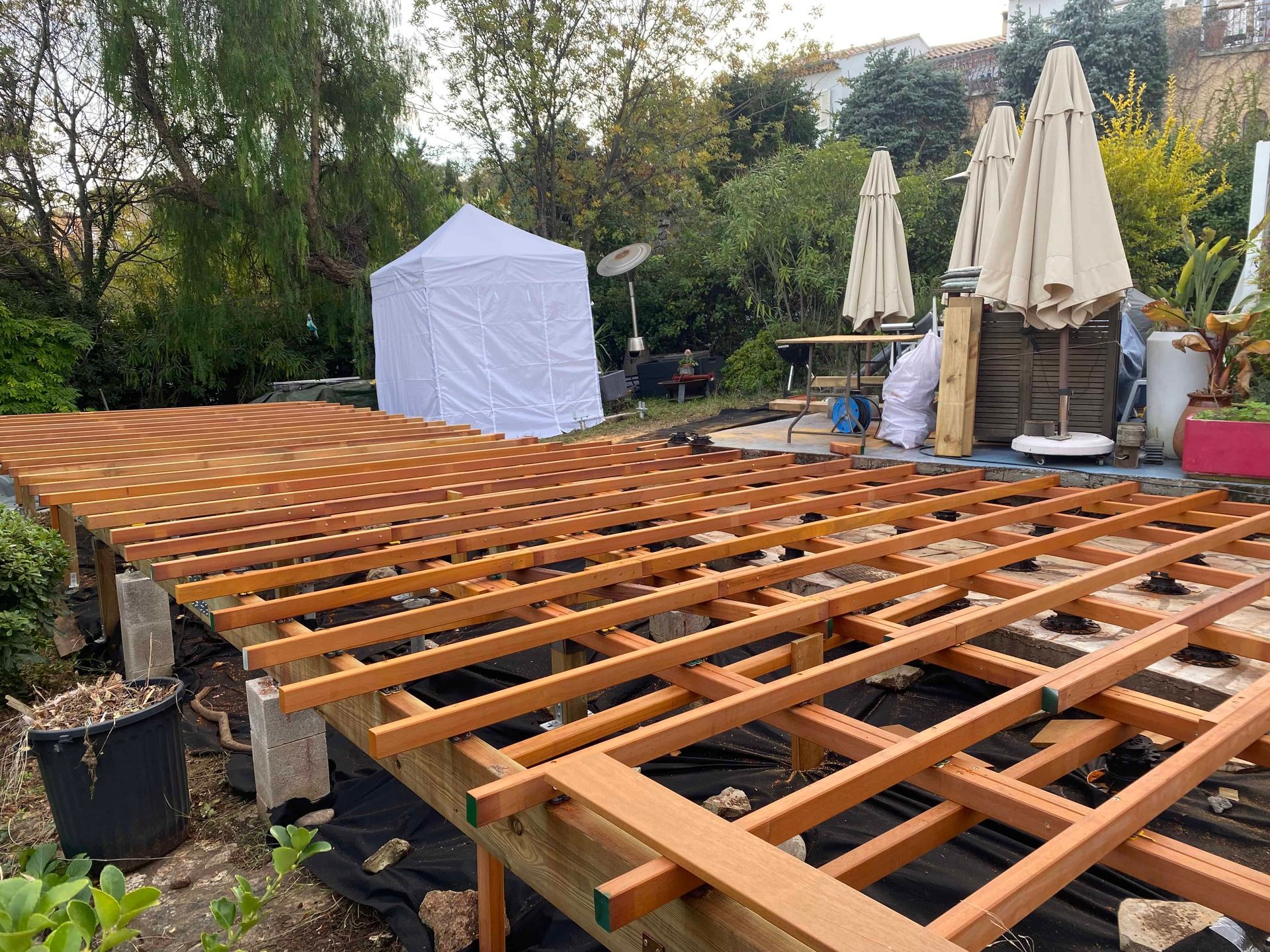 Une terrasse en bois est en cours de construction dans un jardin.