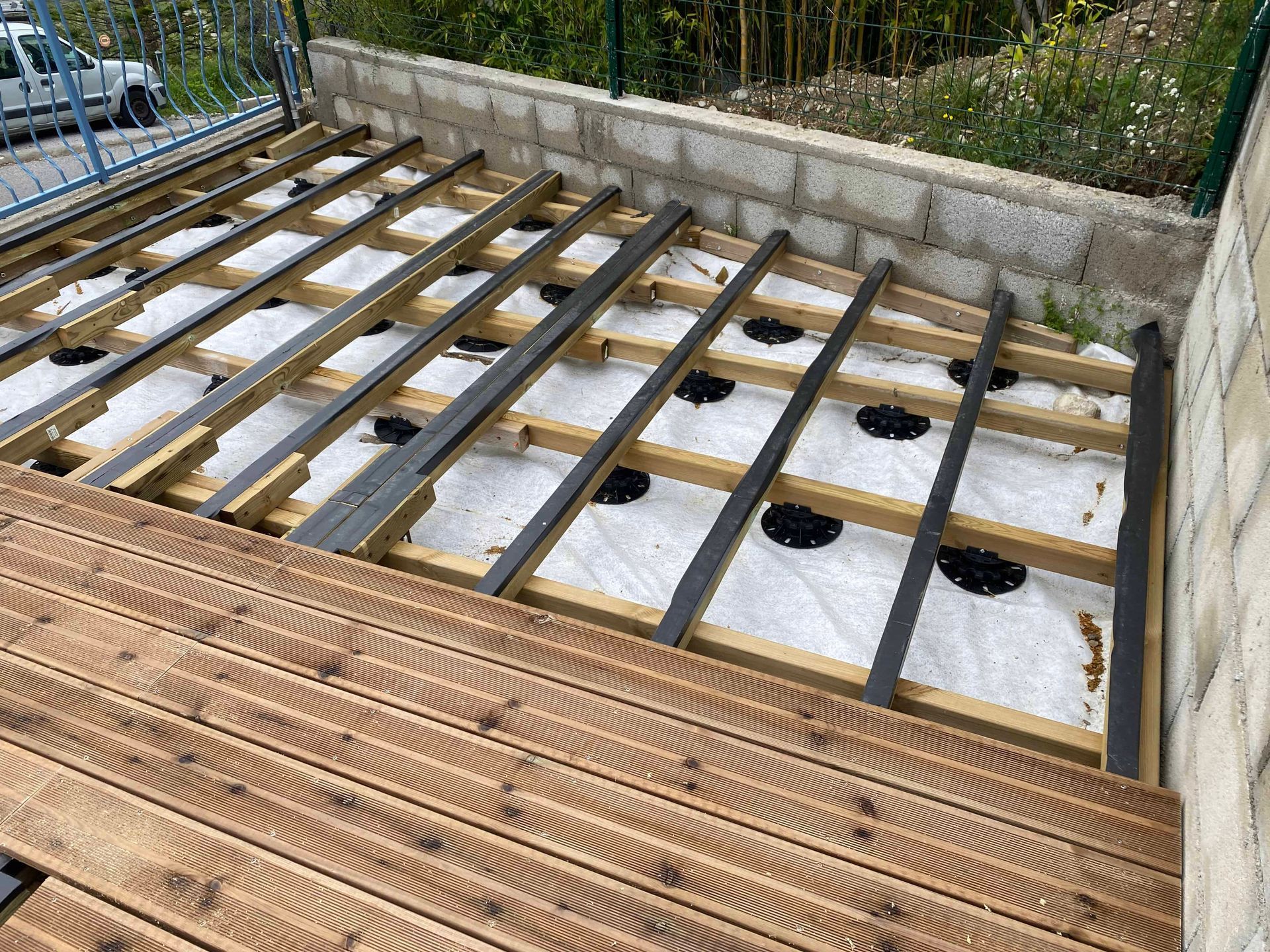 Une terrasse en bois est en train d'être construite sur un mur de briques.