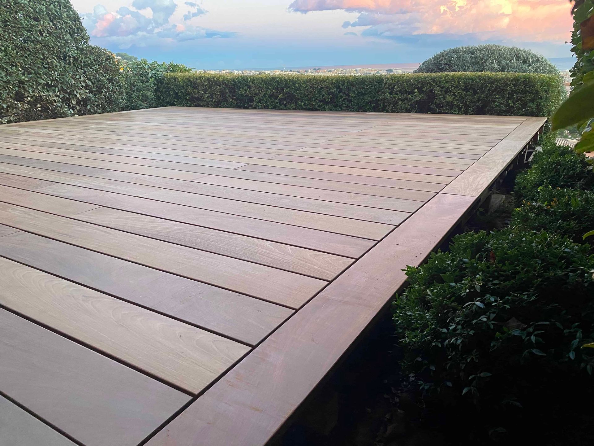 Une terrasse en bois avec un coucher de soleil en arrière-plan