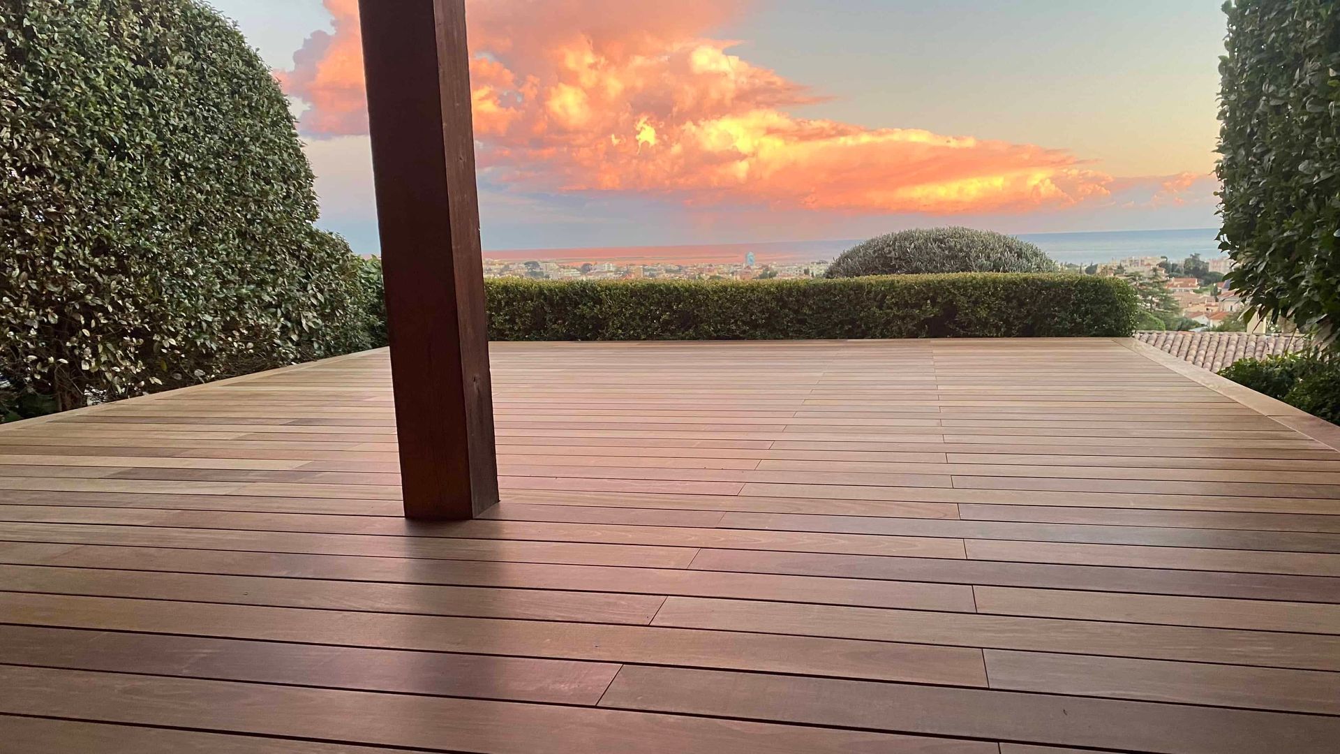 Une terrasse en bois avec vue sur l'océan au coucher du soleil.