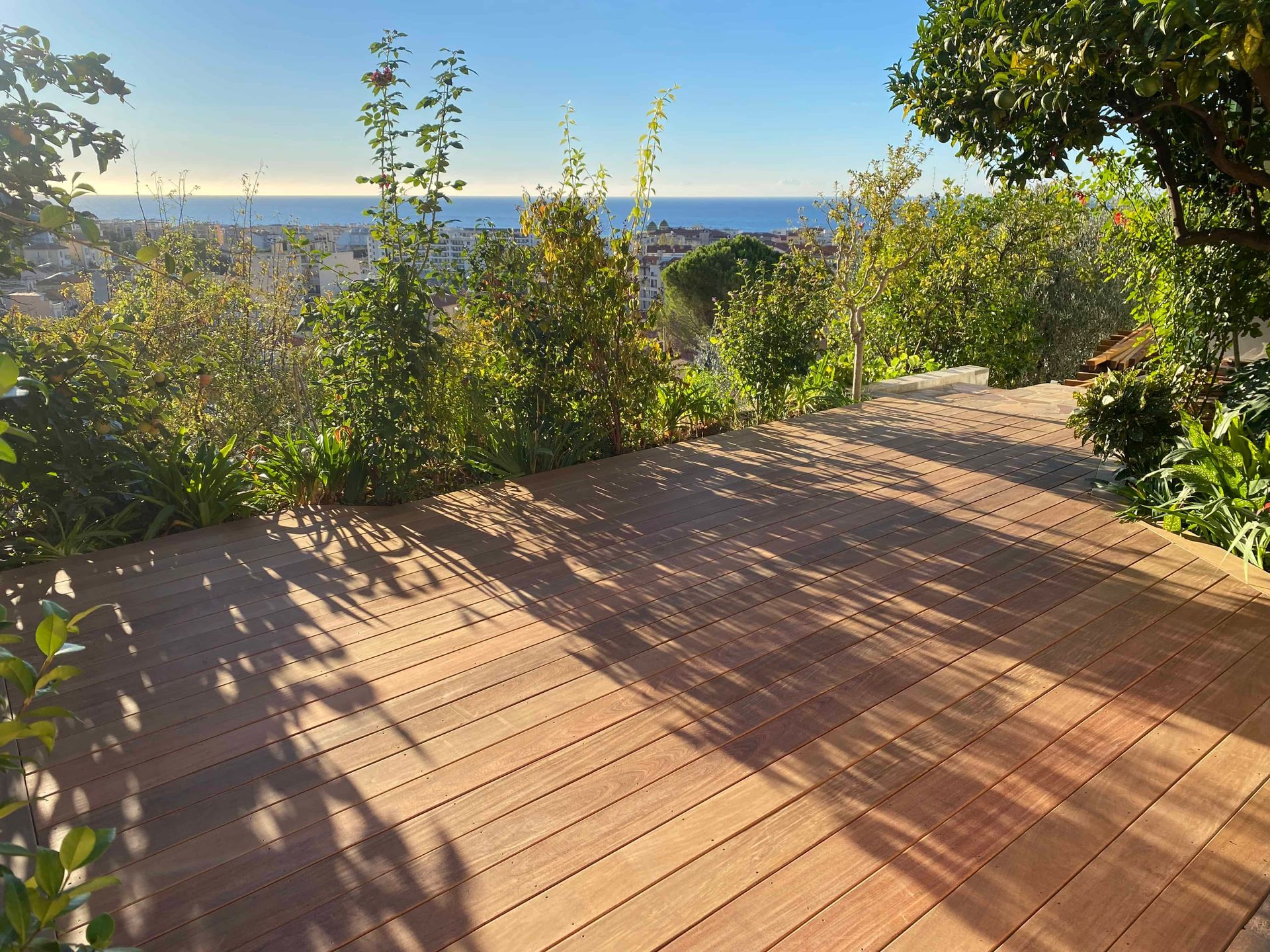 Une terrasse en bois avec vue sur l'océan et les arbres.