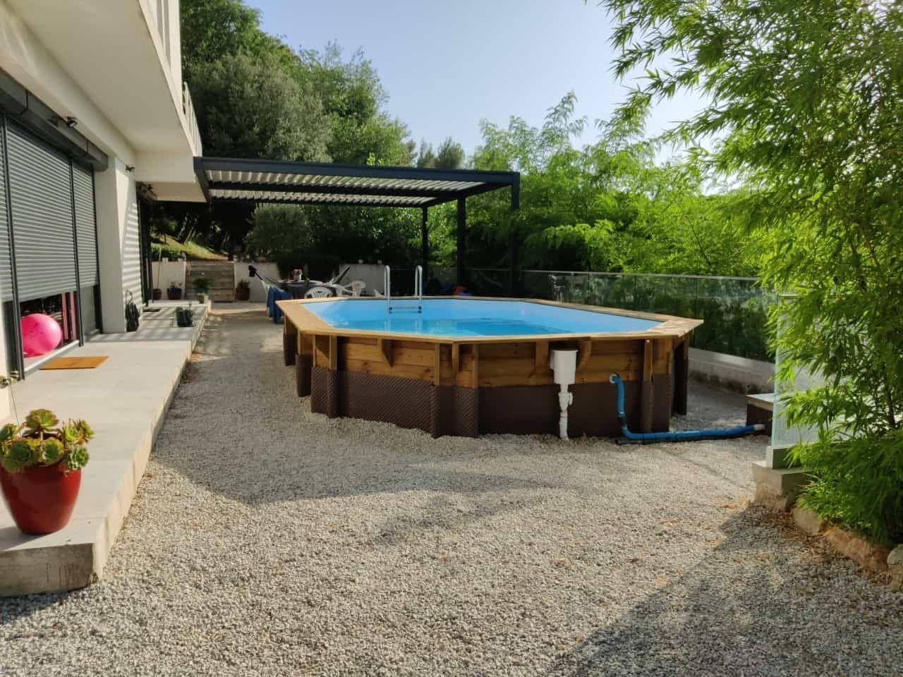 Une grande piscine en bois se trouve dans l'arrière-cour d'une maison.