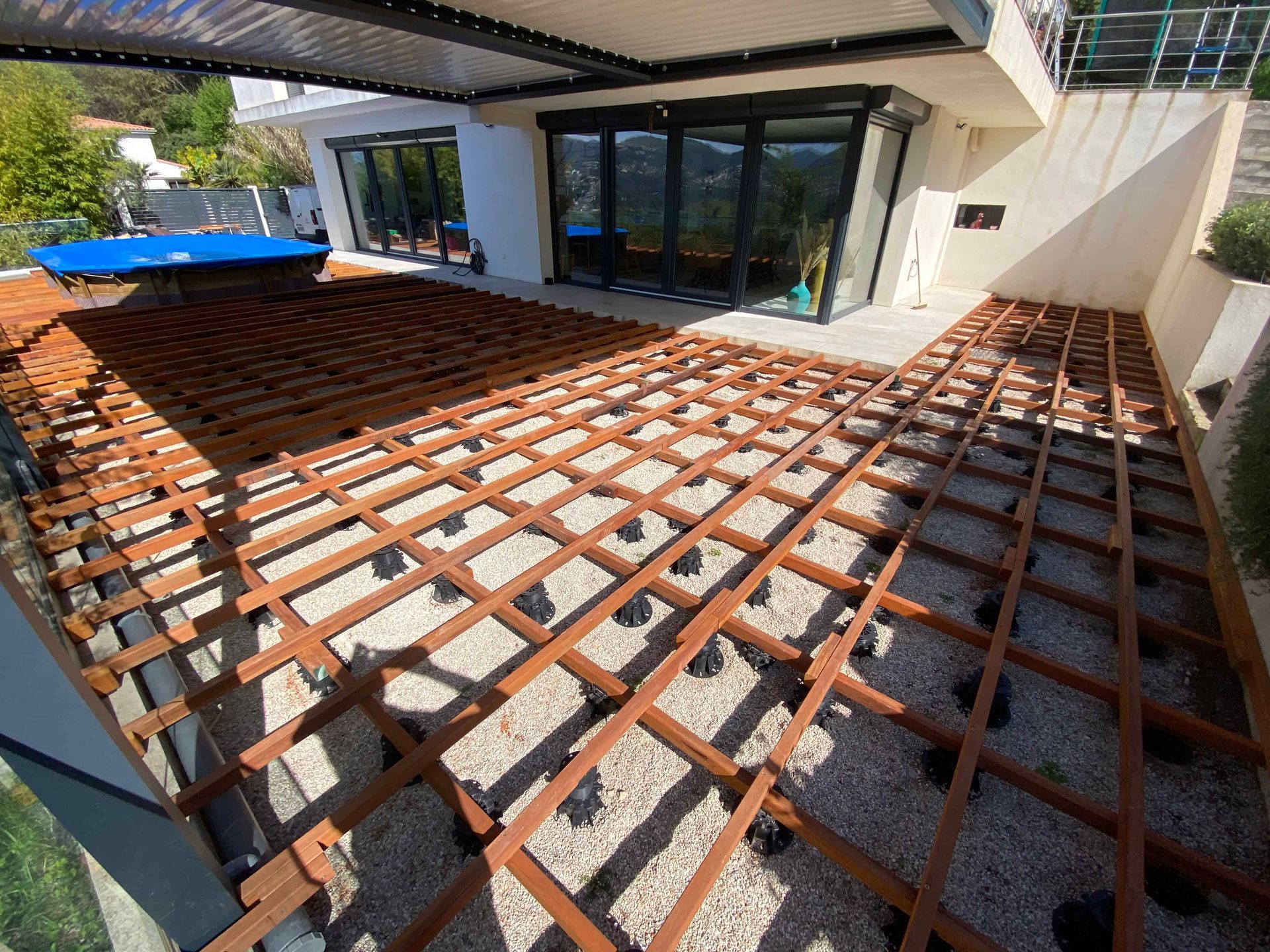 Une terrasse en bois est en cours de construction devant une maison.