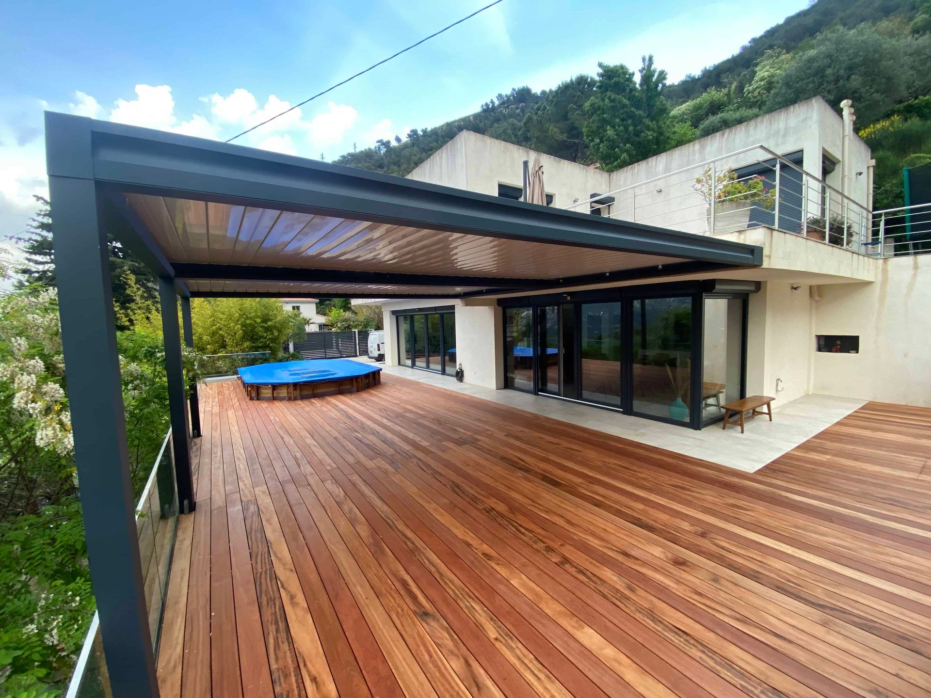 Une grande terrasse en bois avec une pergola au-dessus devant une maison.