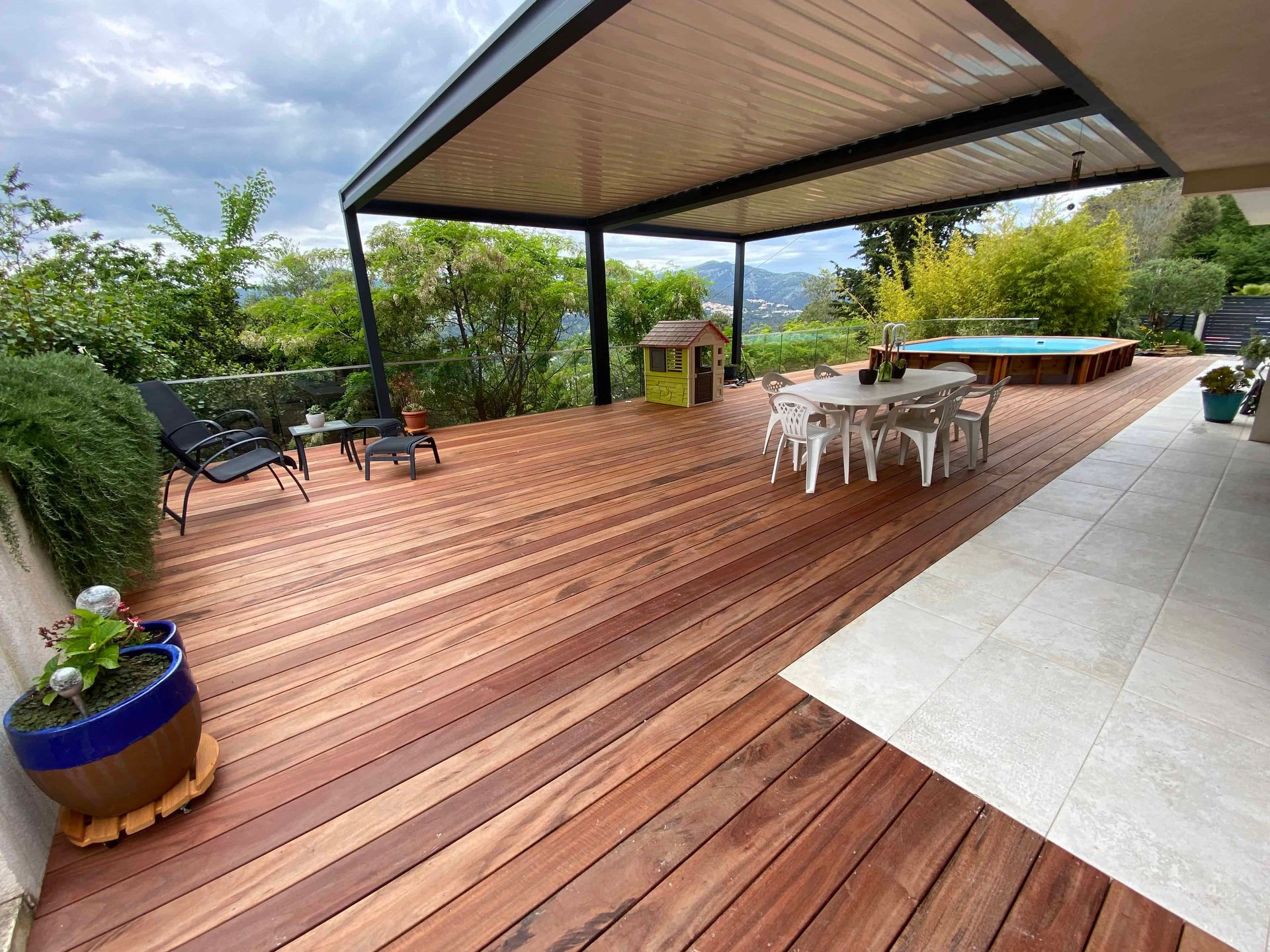 Une terrasse en bois avec une pergola et une table et des chaises dessus.