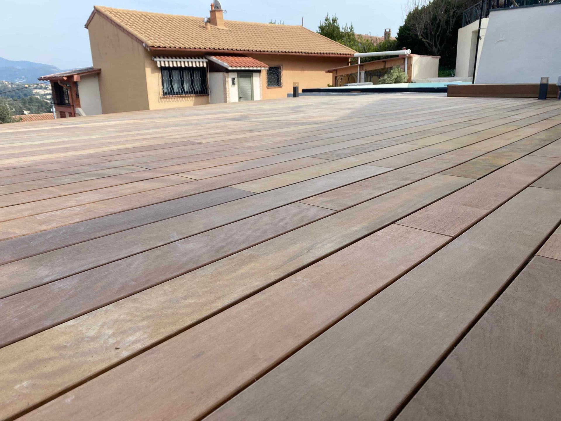 Une terrasse en bois avec une maison en arrière-plan