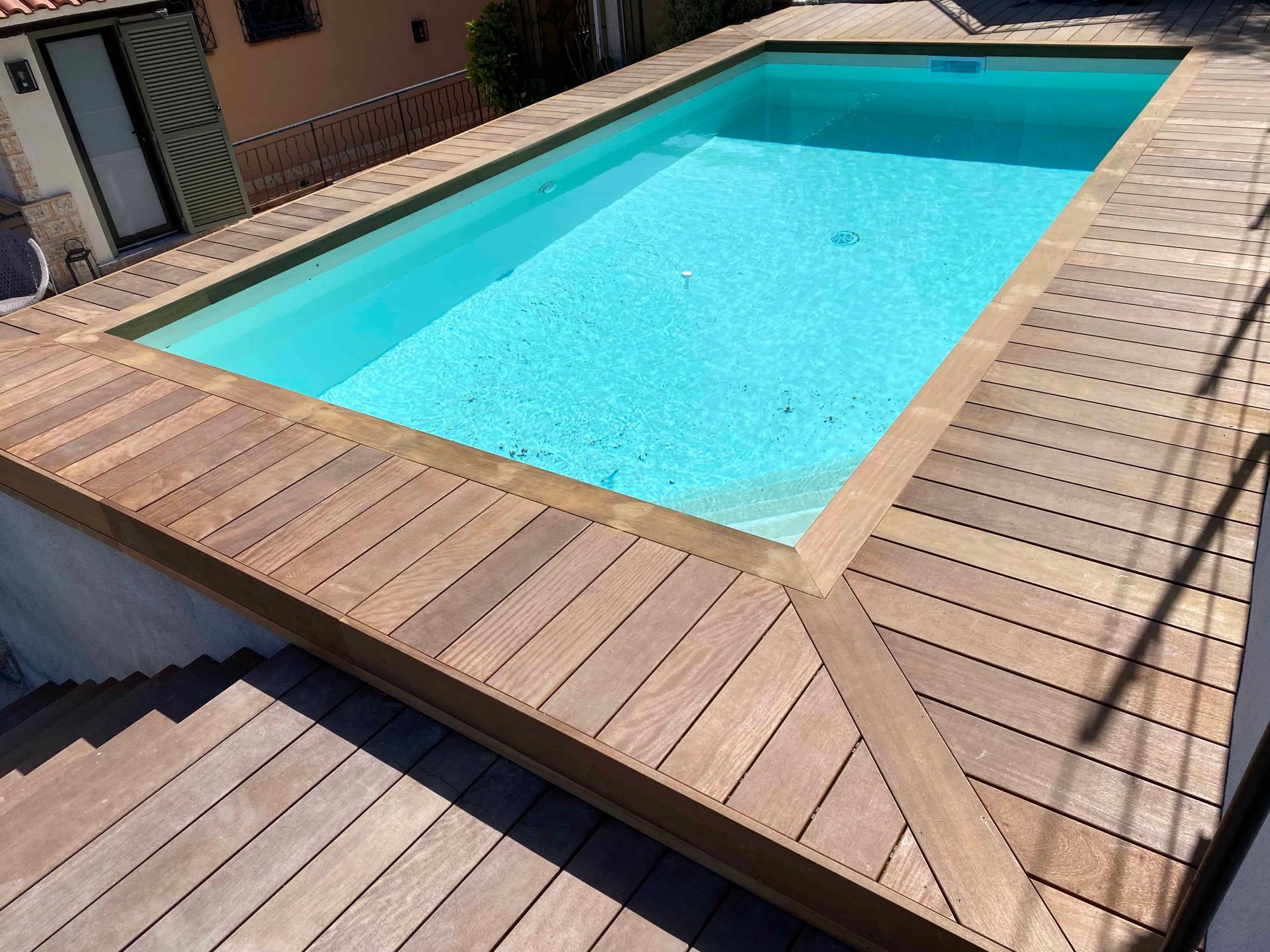 Une grande piscine est entourée d'une terrasse en bois