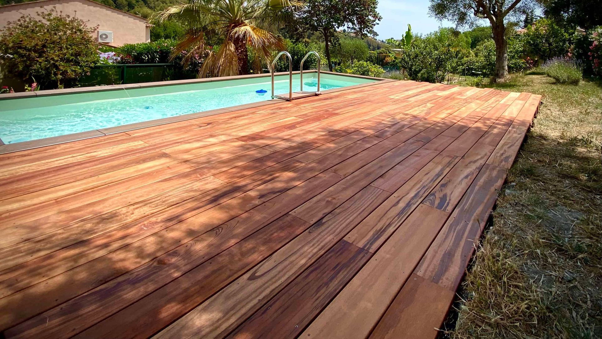 Une terrasse en bois Miuracatiara jouxte une piscine.