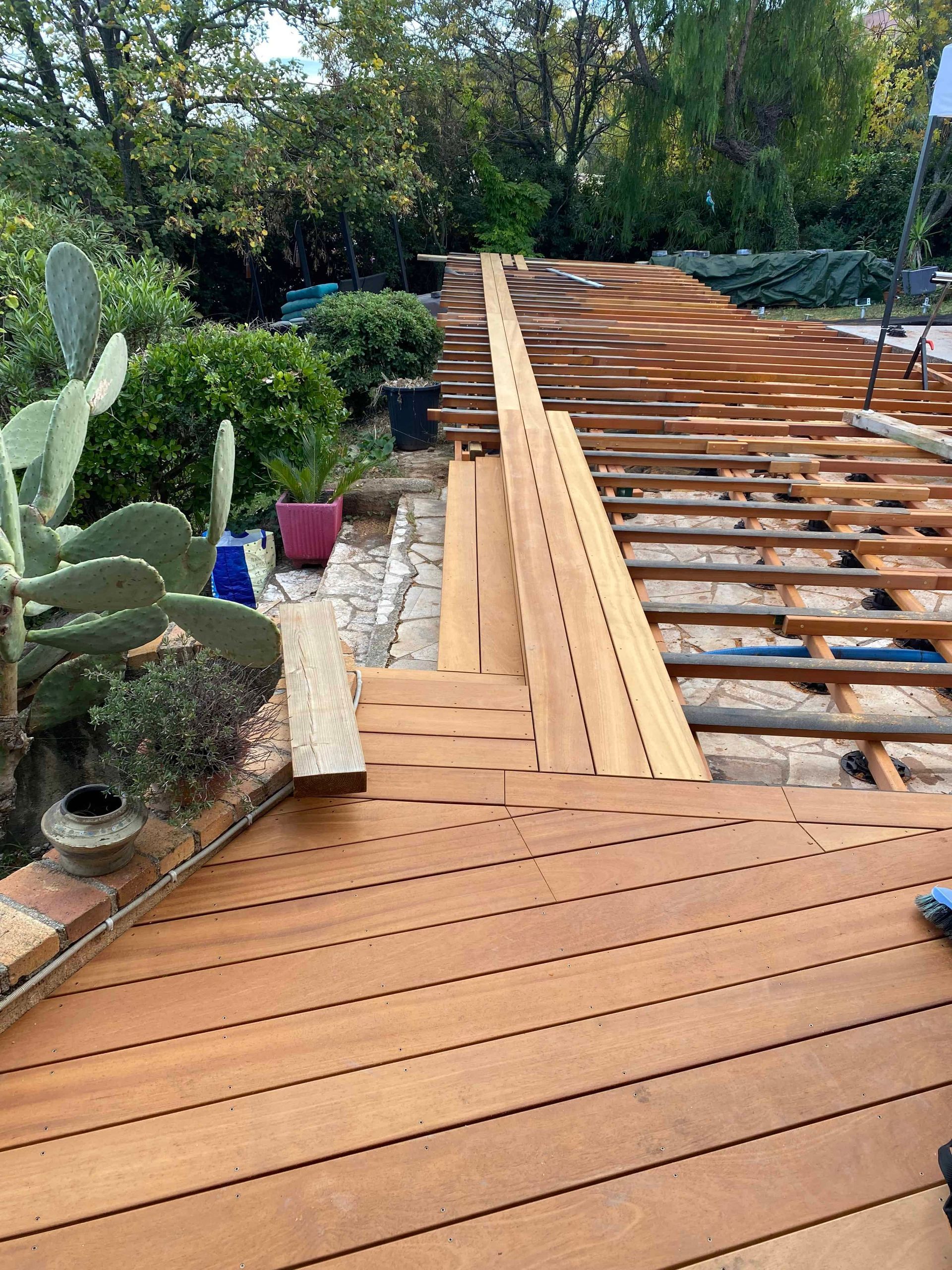 Une terrasse en bois est en cours de construction dans un jardin.