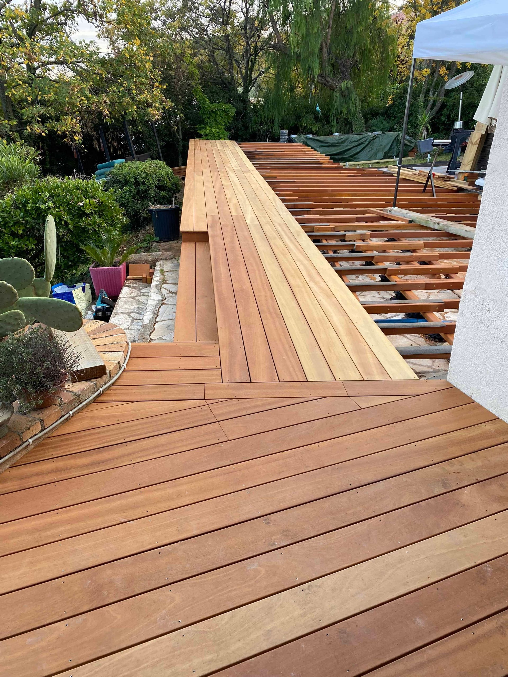 Une terrasse en bois est en cours de construction dans une cour arrière.