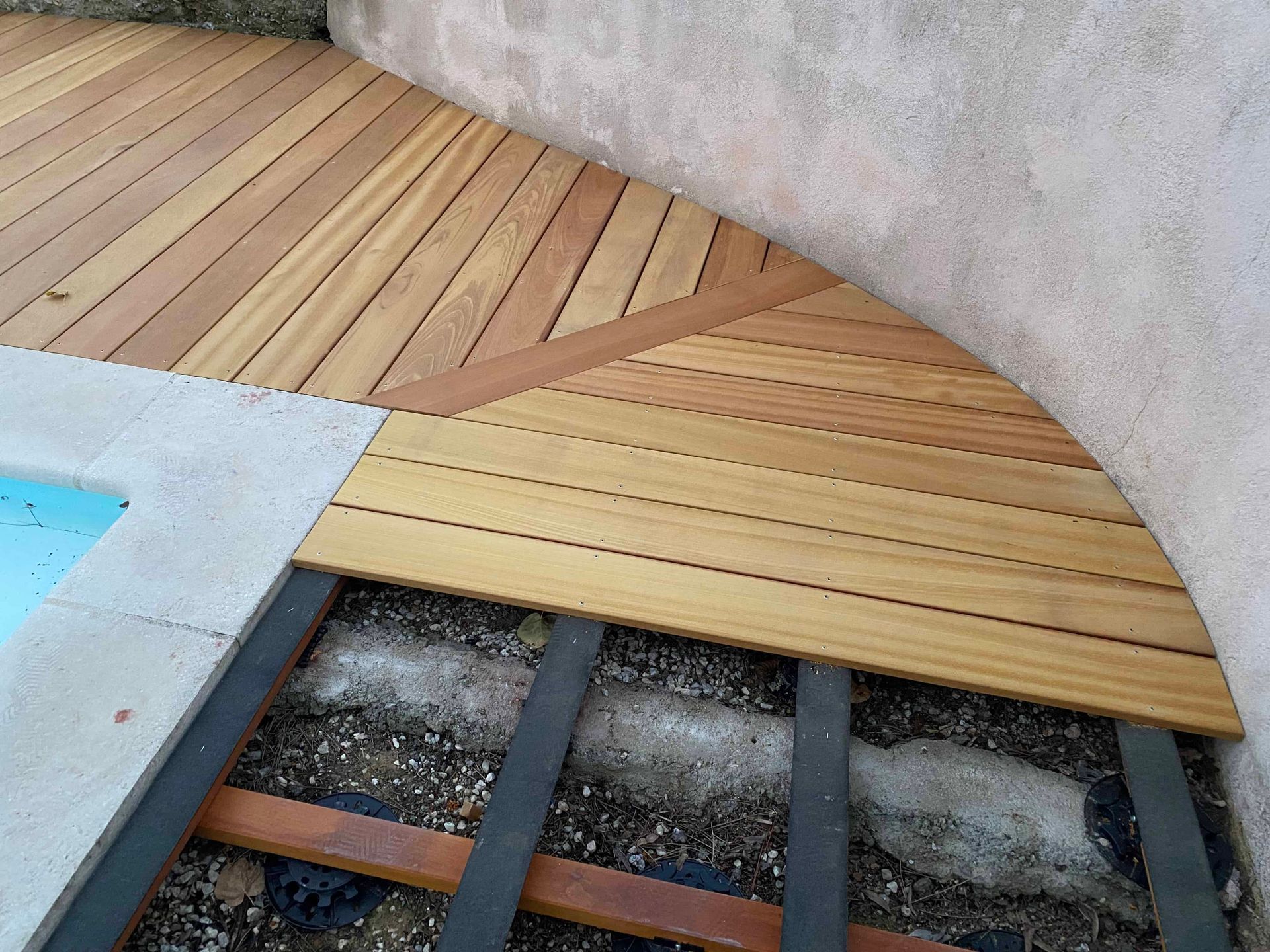 Une terrasse en bois est en cours de construction à côté d'une piscine.