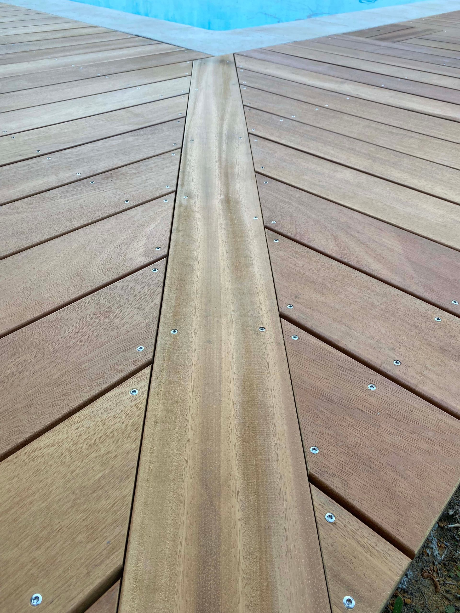 Un gros plan d'une terrasse en bois à côté d'une piscine.
