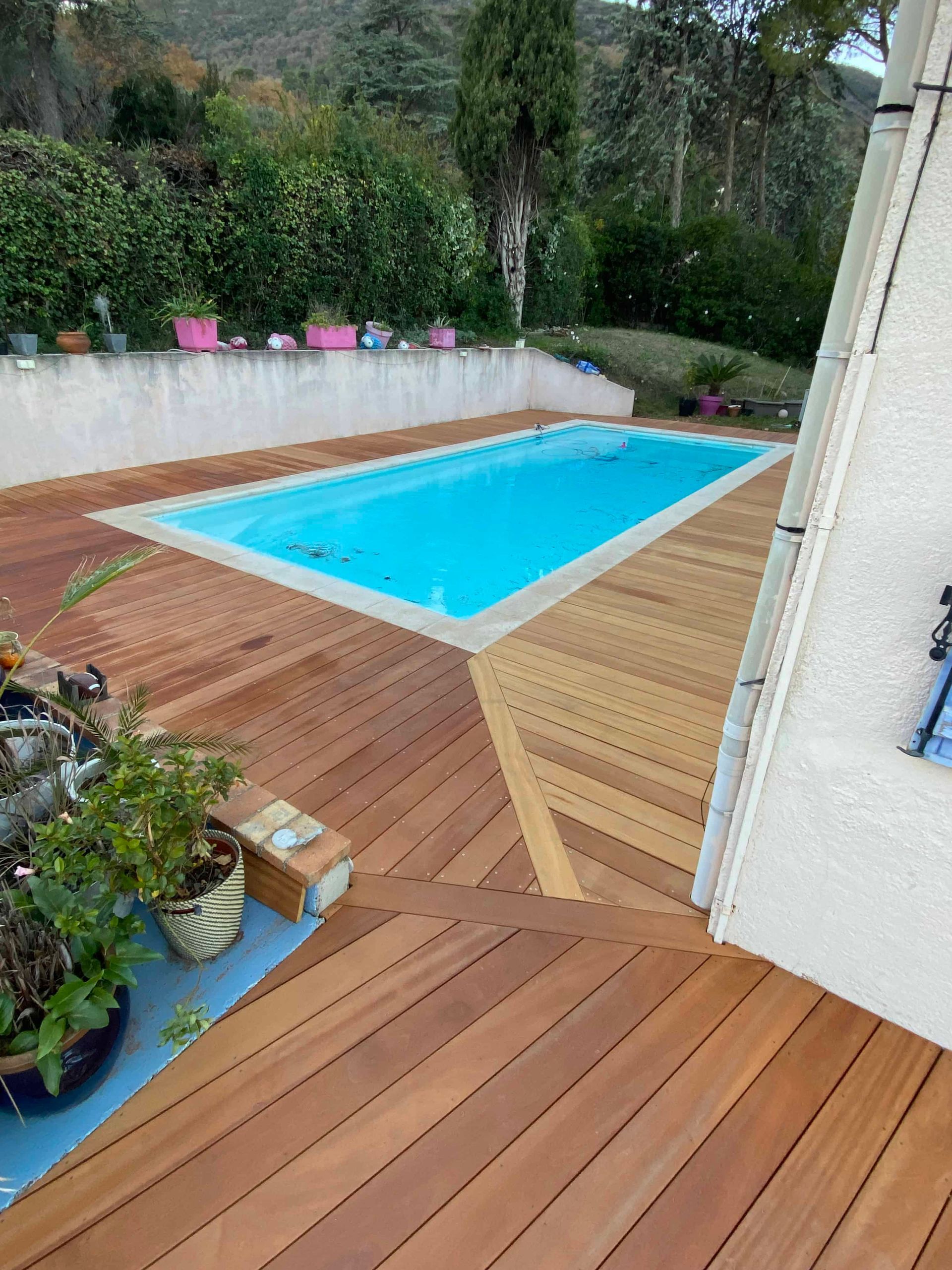 Une grande piscine est entourée d'une terrasse en bois.