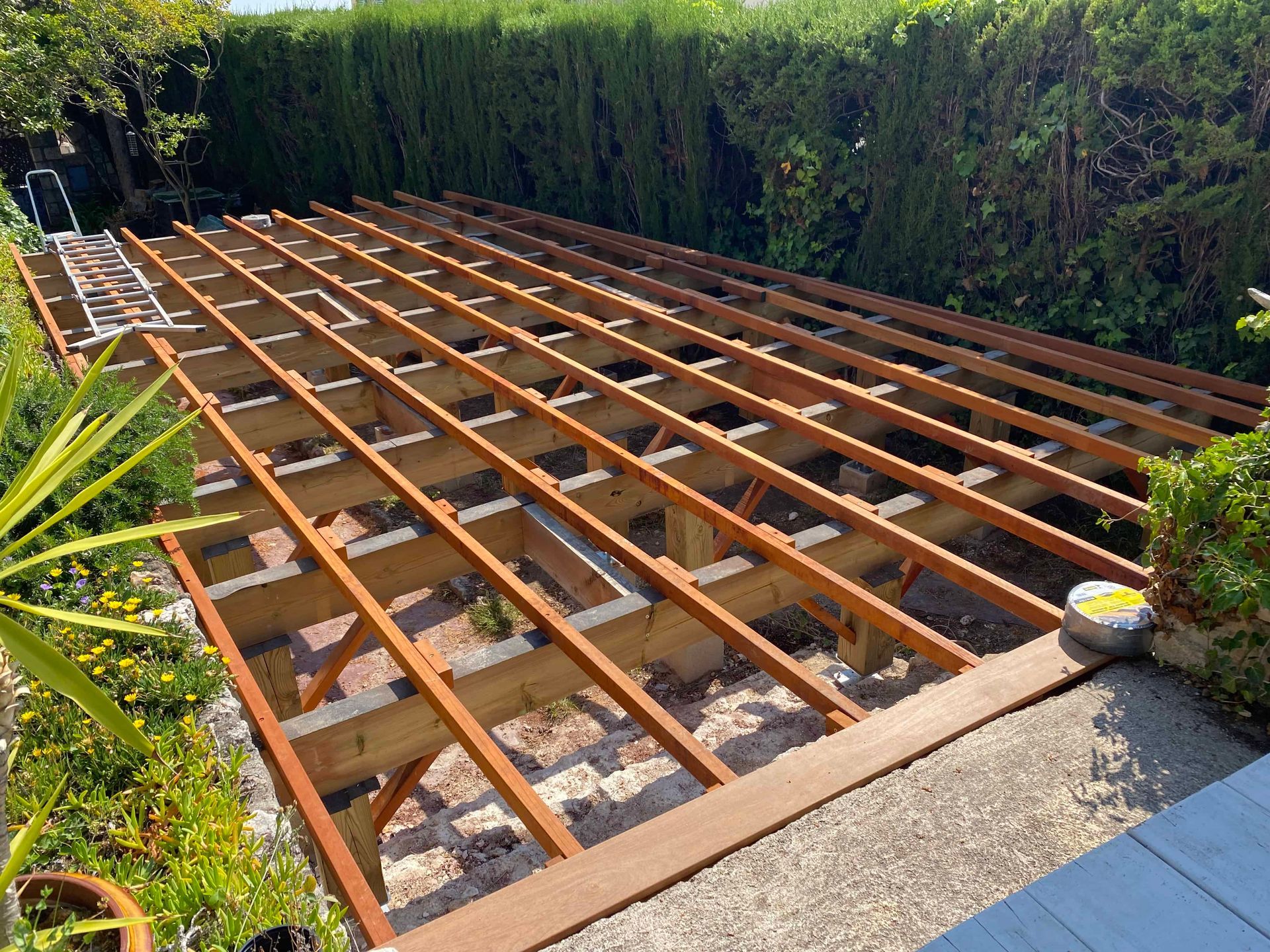 Une terrasse en bois est en cours de construction dans une cour arrière.