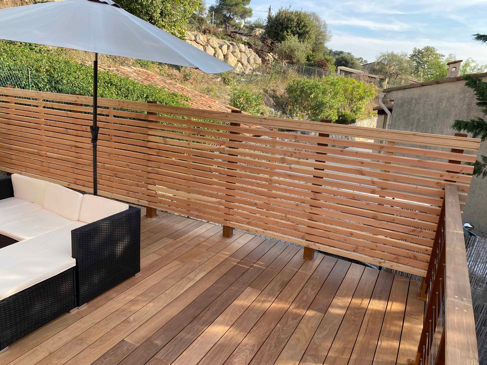Une terrasse en bois avec un canapé et un parasol dessus.
