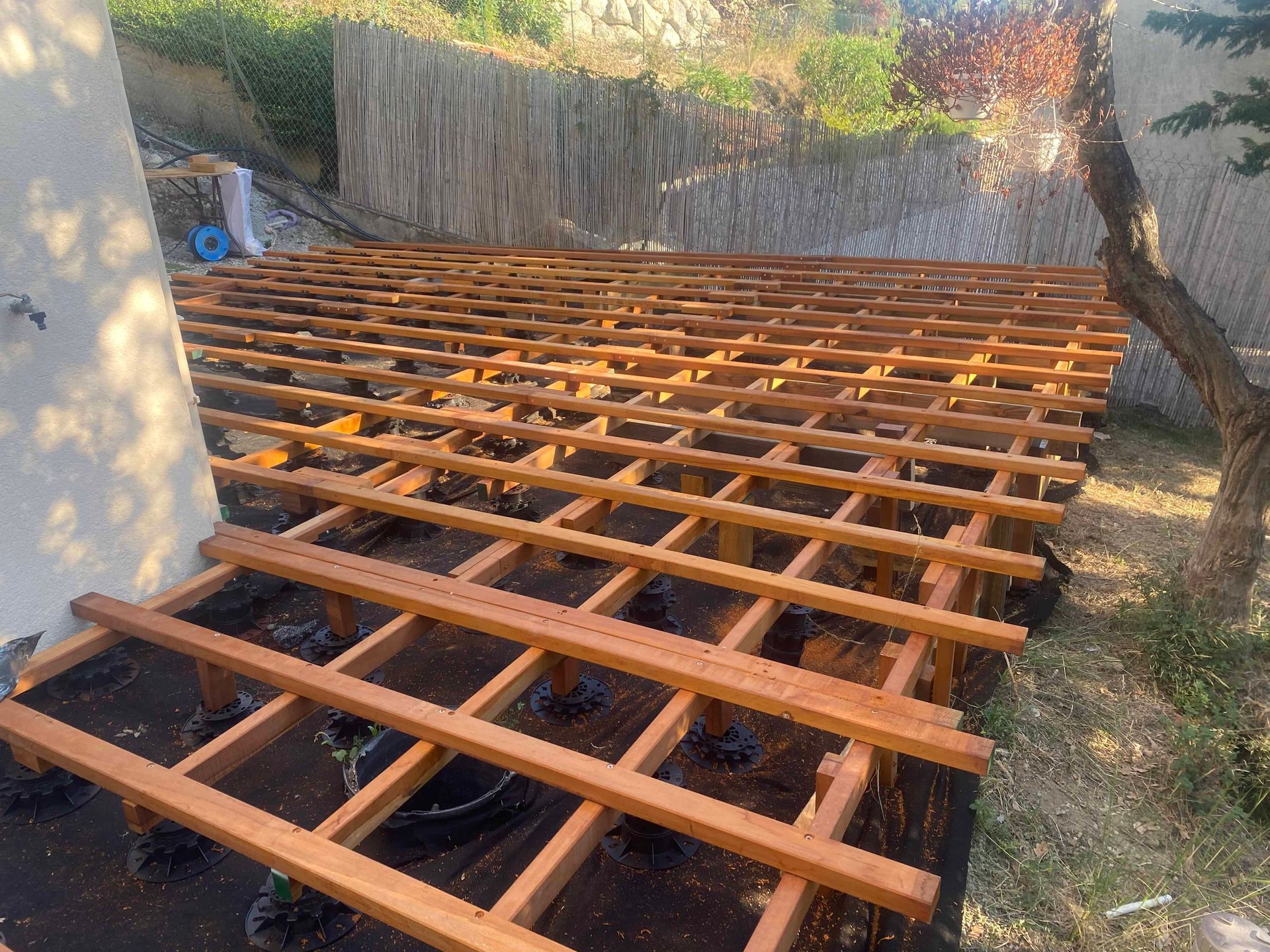 Une terrasse en bois est en cours de construction dans une cour arrière.