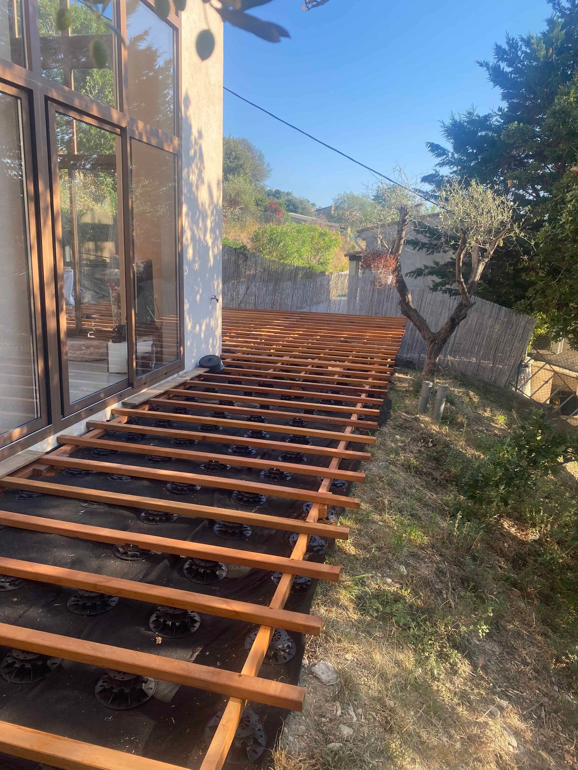 Une terrasse en bois est en cours de construction dans l'arrière-cour d'une maison.