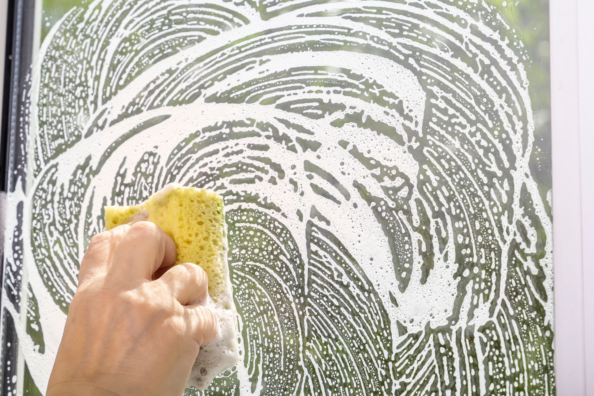 A person is cleaning a window with a sponge.