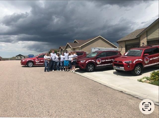 Group of people standing with red vehicles in a residential area under a cloudy sky.