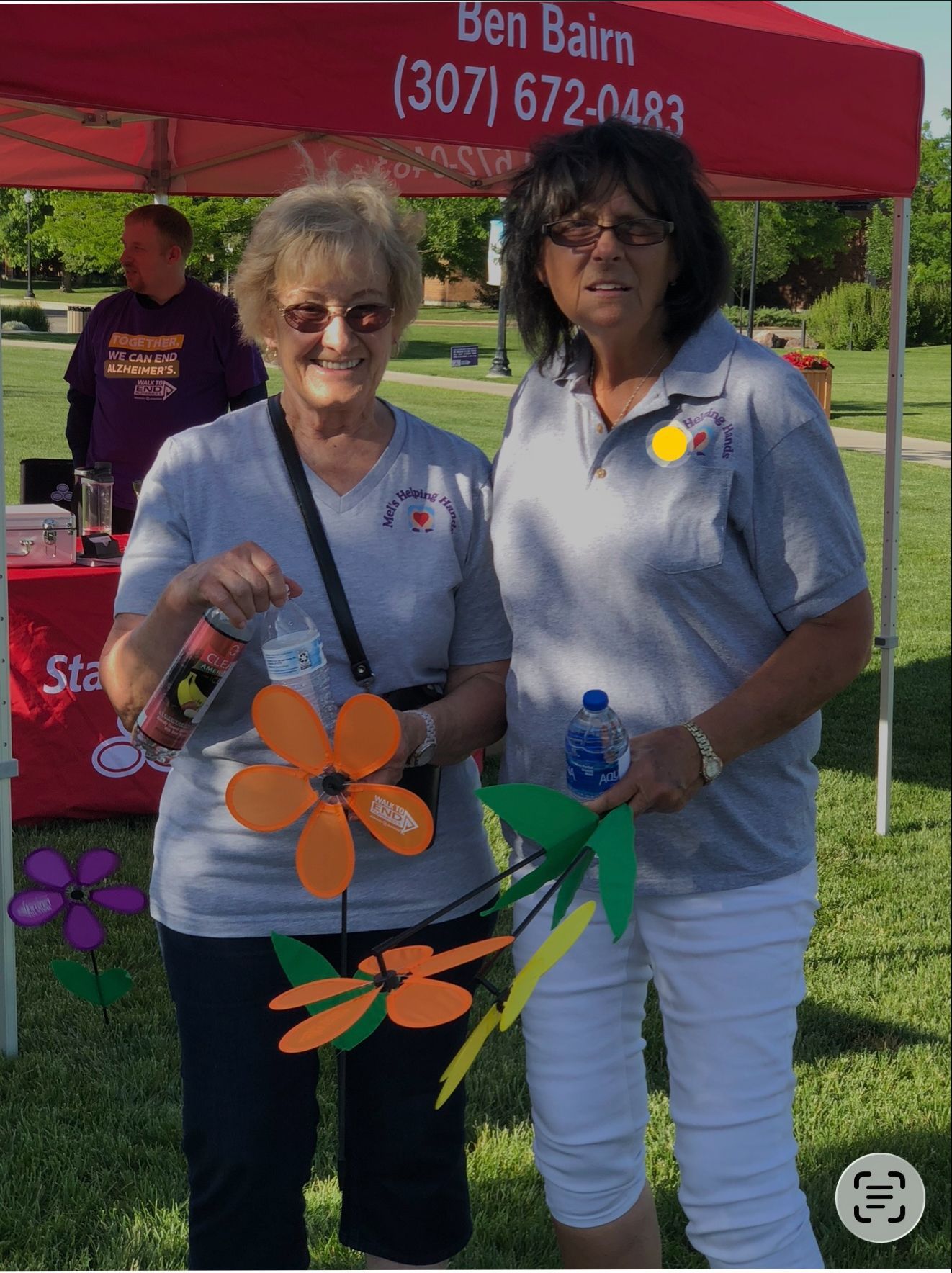 Two women with paper flowers at a booth, 
